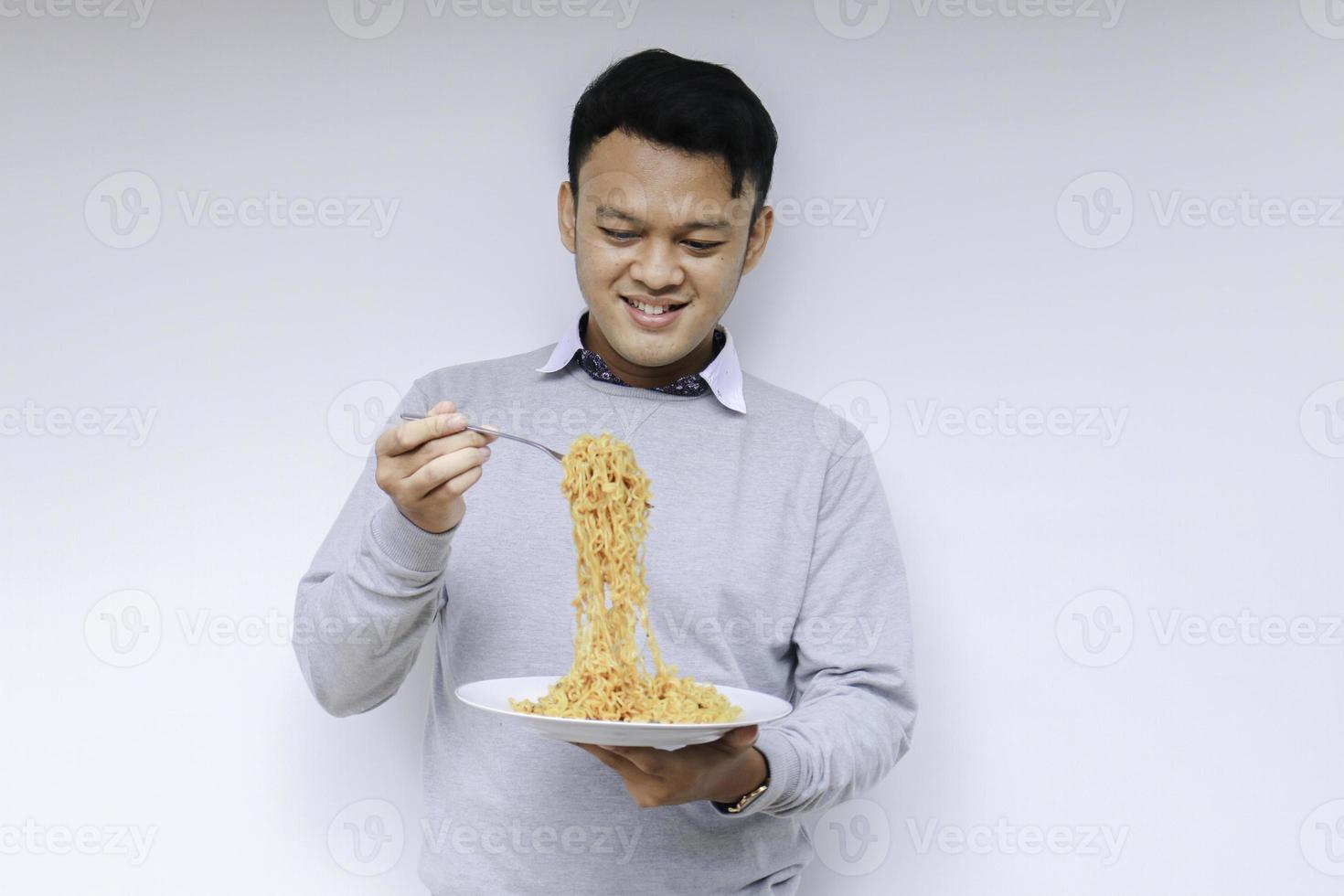 Portrait of happy Young Asian man enjoys noodles. Eating lunch concept. photo