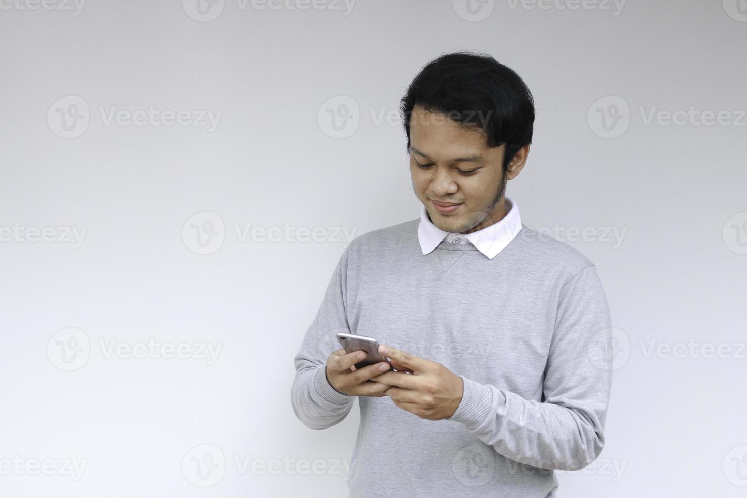 Smart Young asian man is happy and smiling when using smartphone in studio background photo