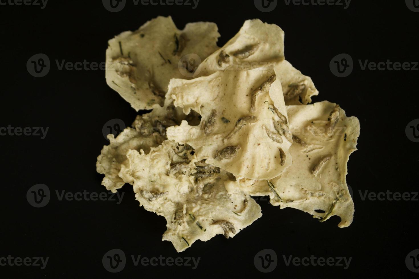 Rempeyek or fish crackers on wooden plate with salt fish isolated on white background. Fried savory Javanese crackers. photo