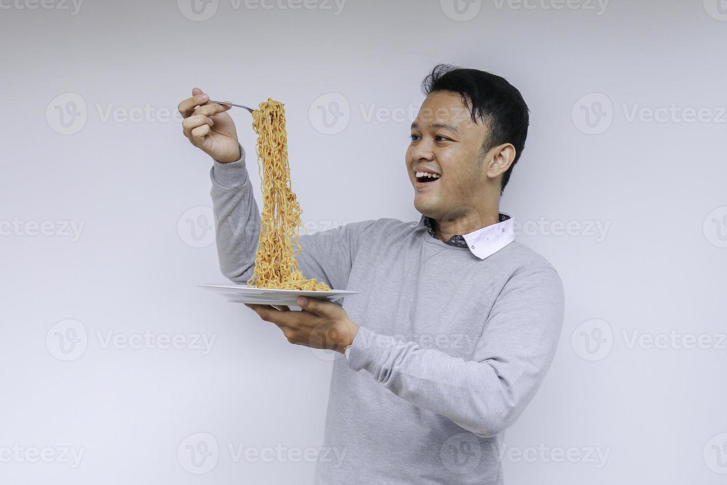 Portrait of happy Young Asian man enjoys noodles. Eating lunch concept. photo