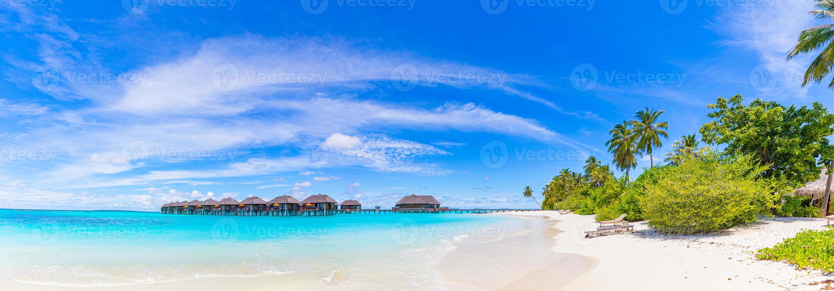 Amazing panorama at Maldives. Luxury resort villas seascape with palm trees, white sand and blue sky. Beautiful summer landscape. Amazing beach background for vacation holiday. Paradise island concept photo