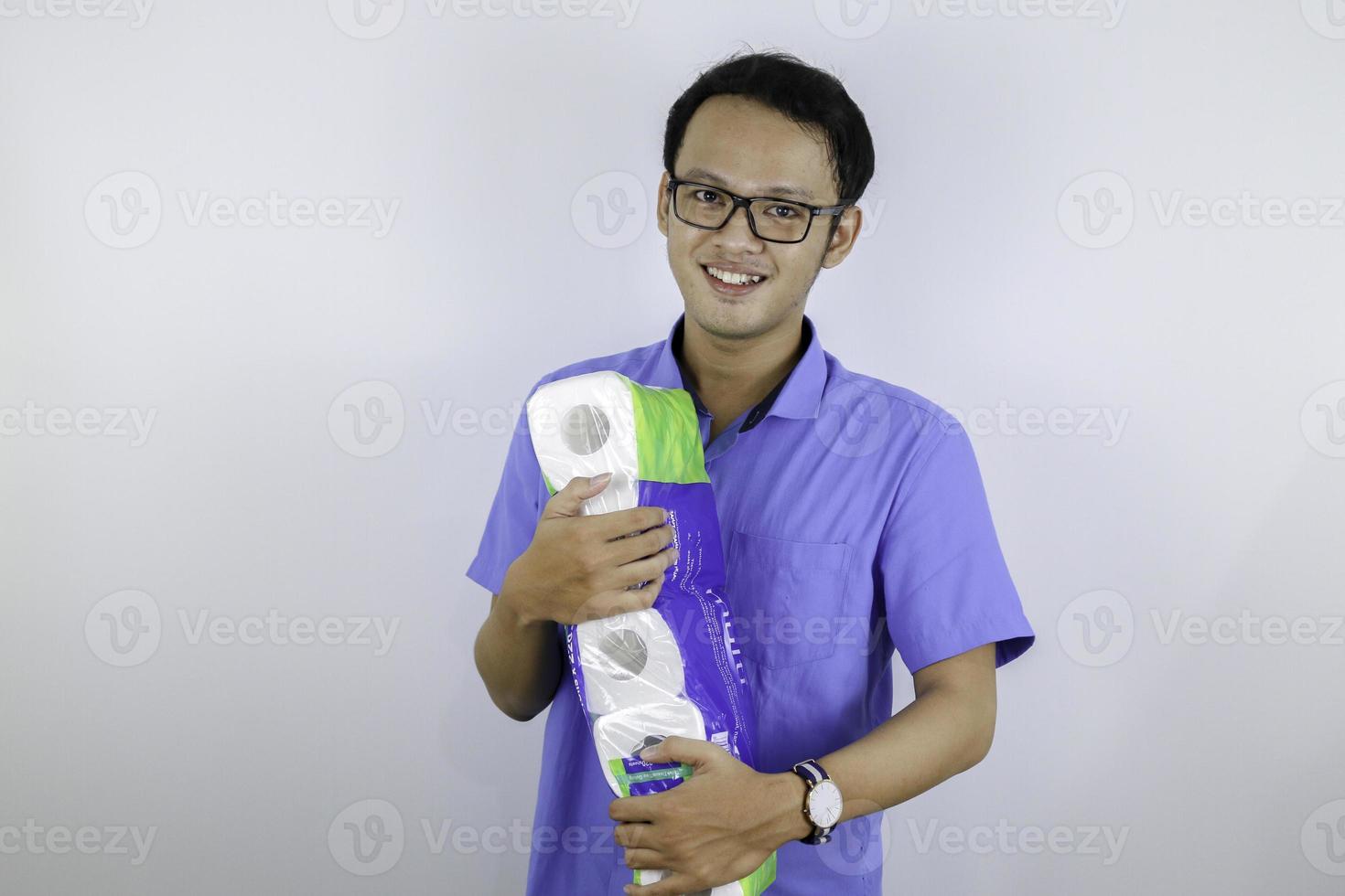 Asian Man is smile and happy when shopping bag with tissue toilet paper rolls. Buying panic for home quarantine due to coronavirus. Stay at home for covid-19 protection concept. photo