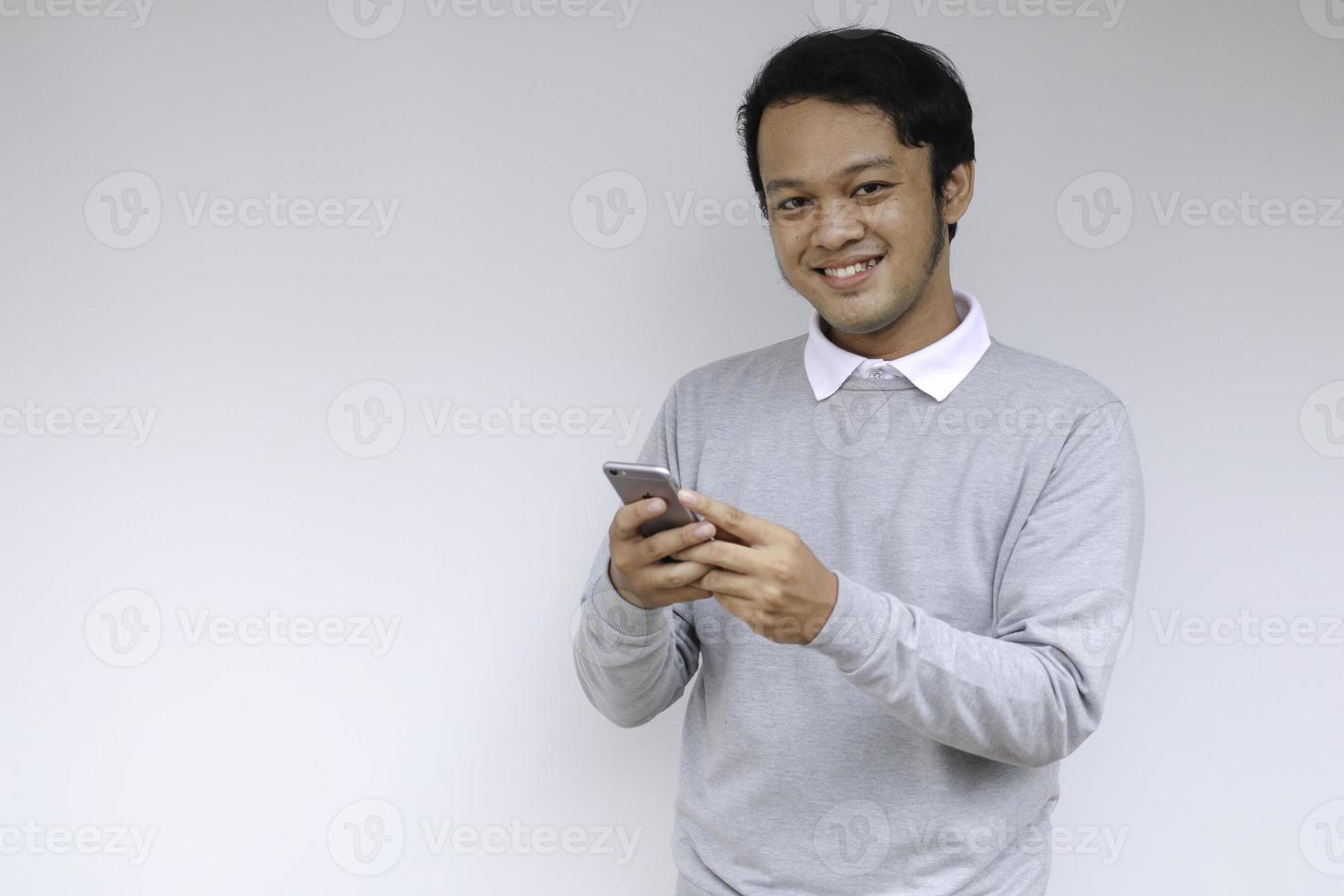 Smart Young asian man is happy and smiling when using smartphone in studio background photo
