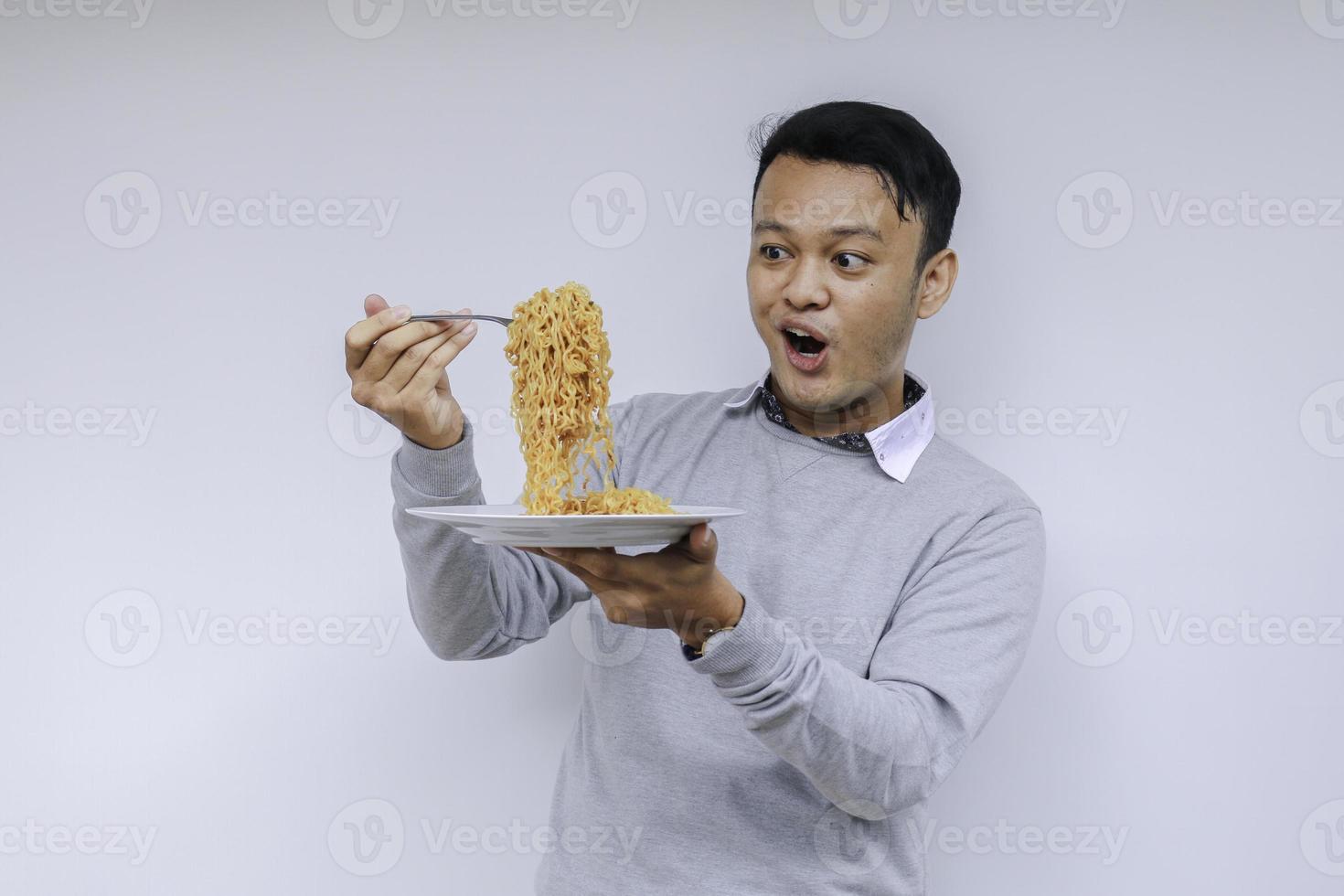 Portrait of Shock and Wow Young Asian man enjoy noodles. Eating lunch concept. photo