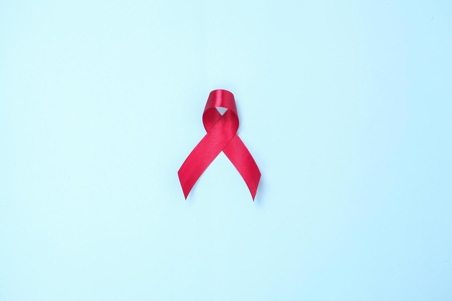 AIDS symbol red ribbon against HIV virus isolated on blue background photo