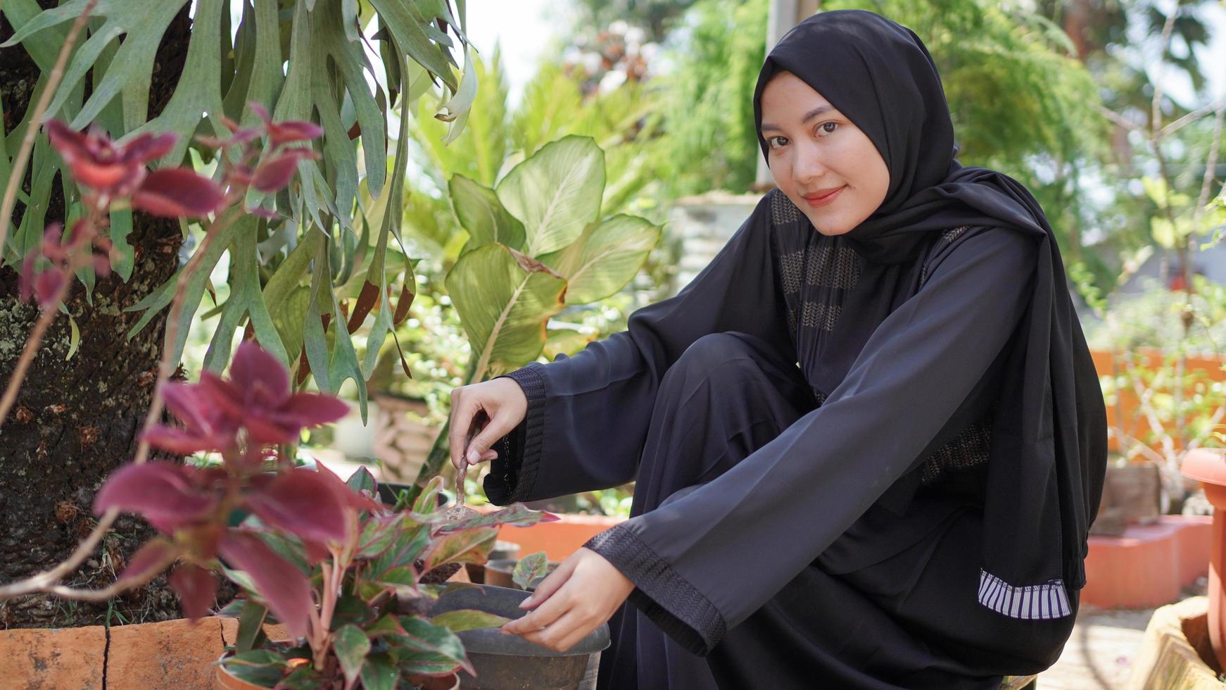 la belleza en hiyab a la que le gusta plantar flores en el jardín foto