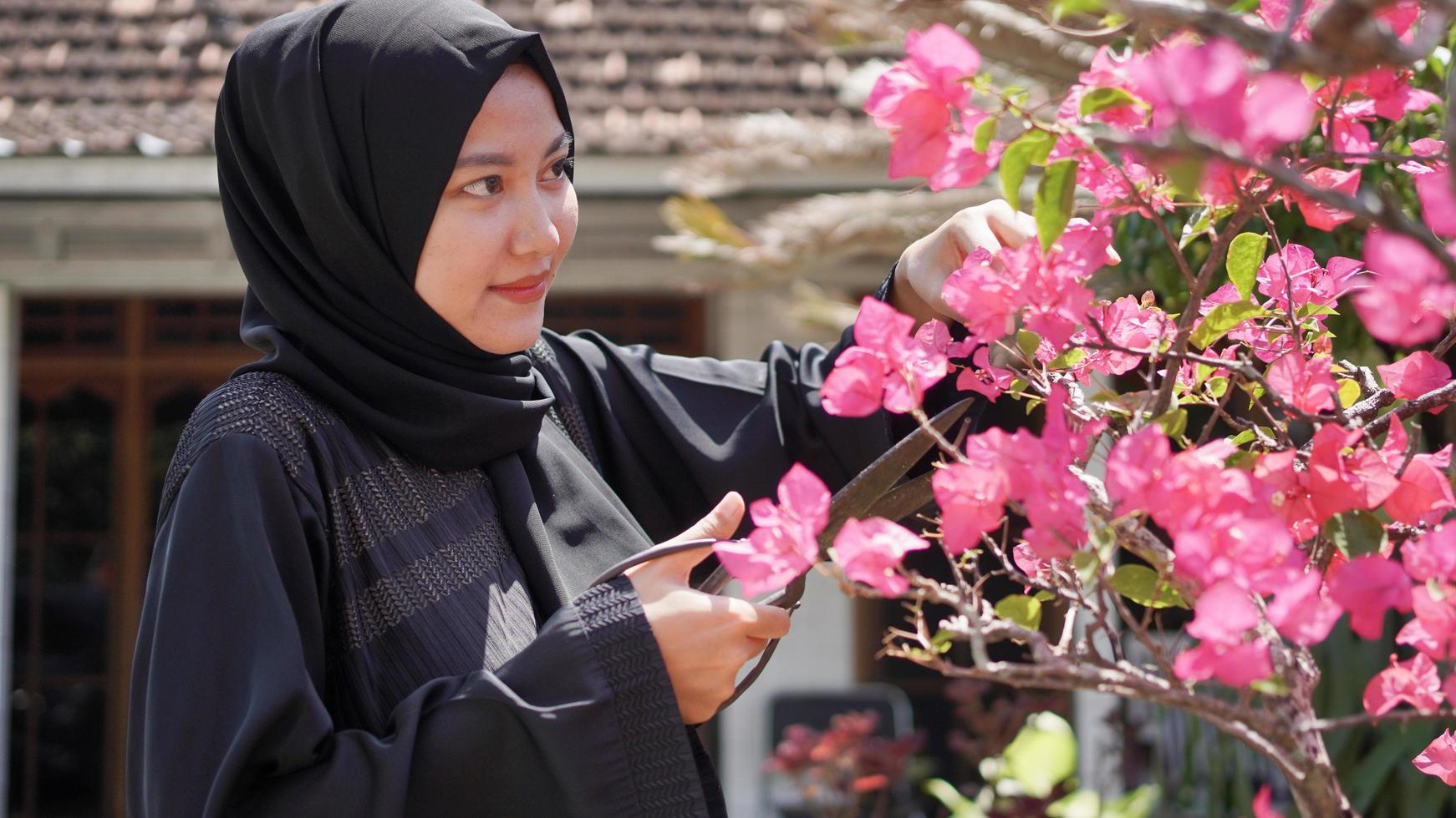 The beauty in hijab is gardening, cutting flowers so that they are neat in the garden photo