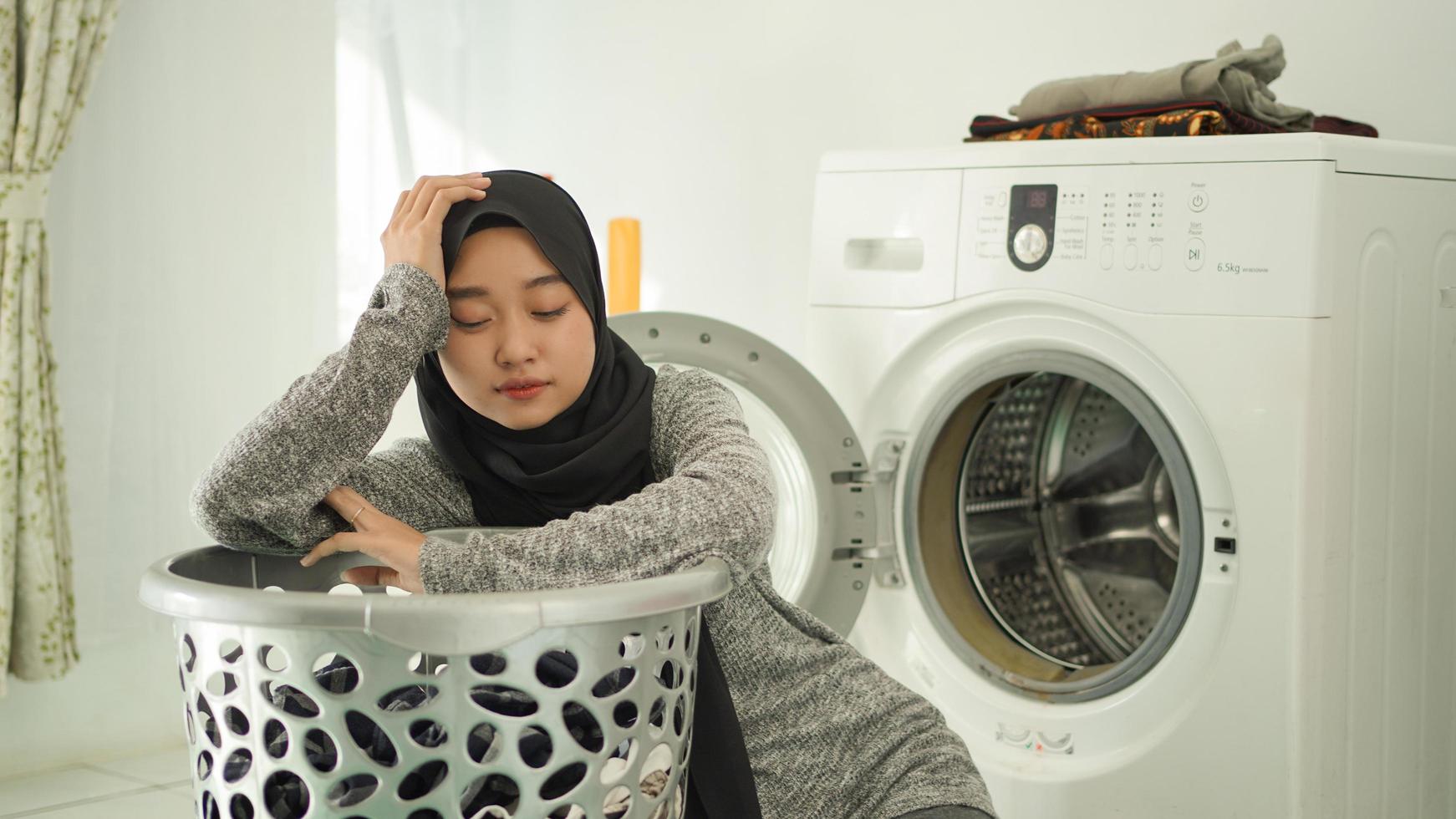 joven asiática resiente ver ropa sucia en casa foto