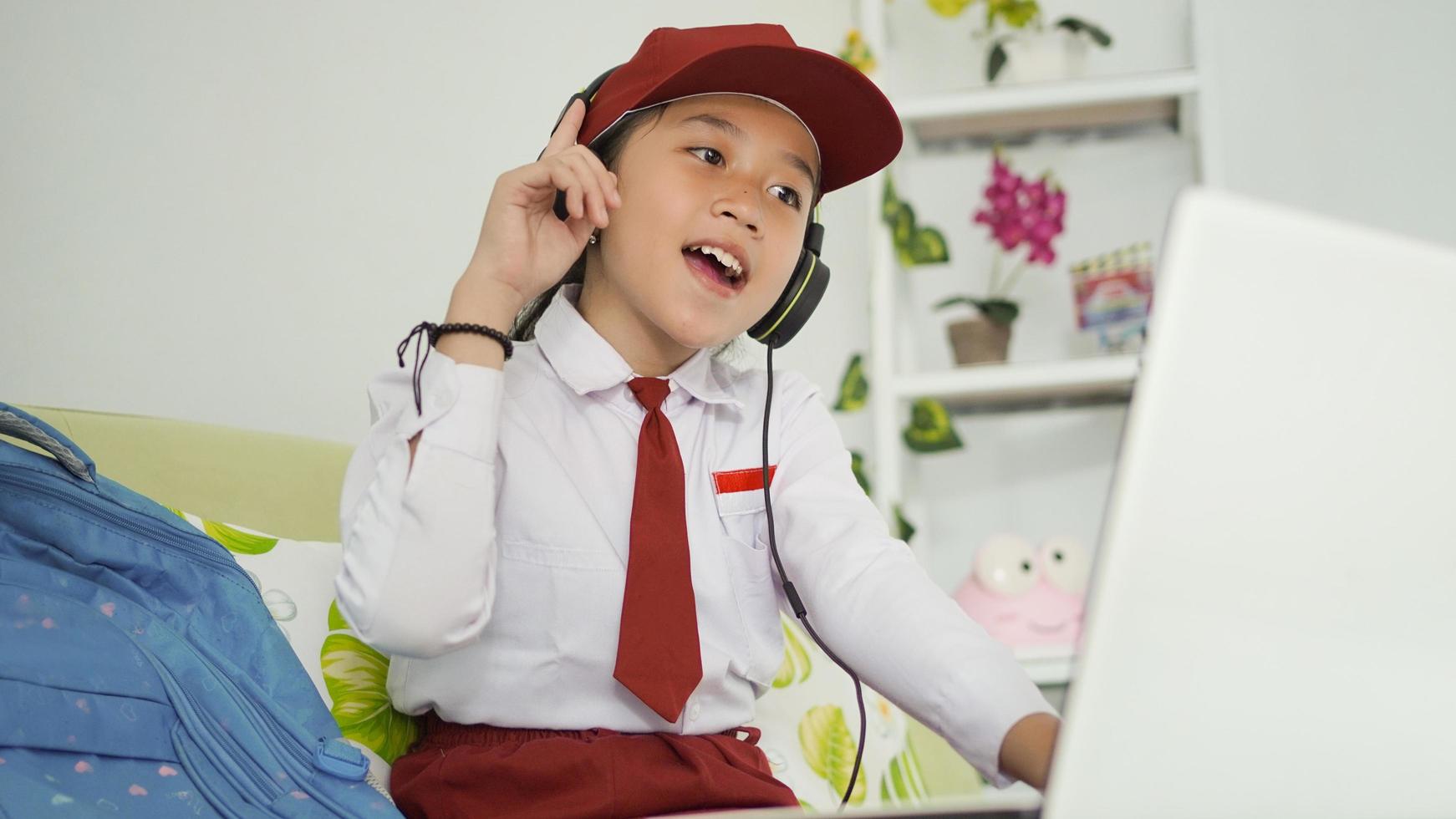 niña de escuela primaria asiática en línea estudiando apasionadamente desde casa foto