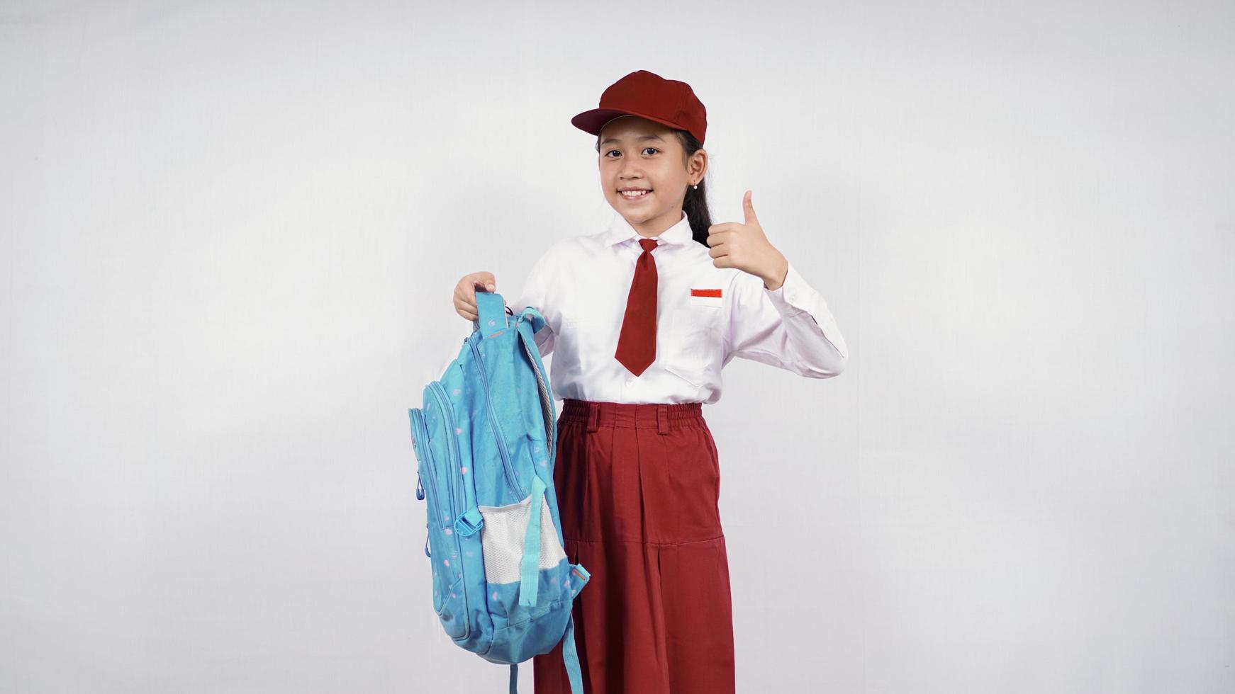 Asian elementary school girl carrying bag and okay isolated on white background photo