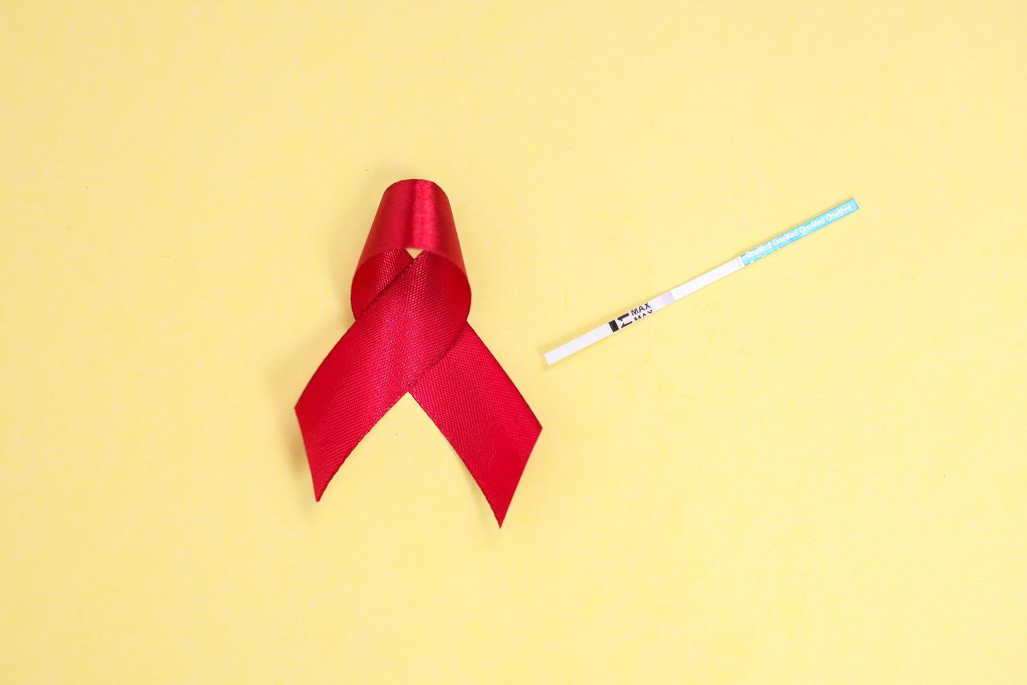 red ribbon and test pack symbol against HIV isolated on yellow background photo