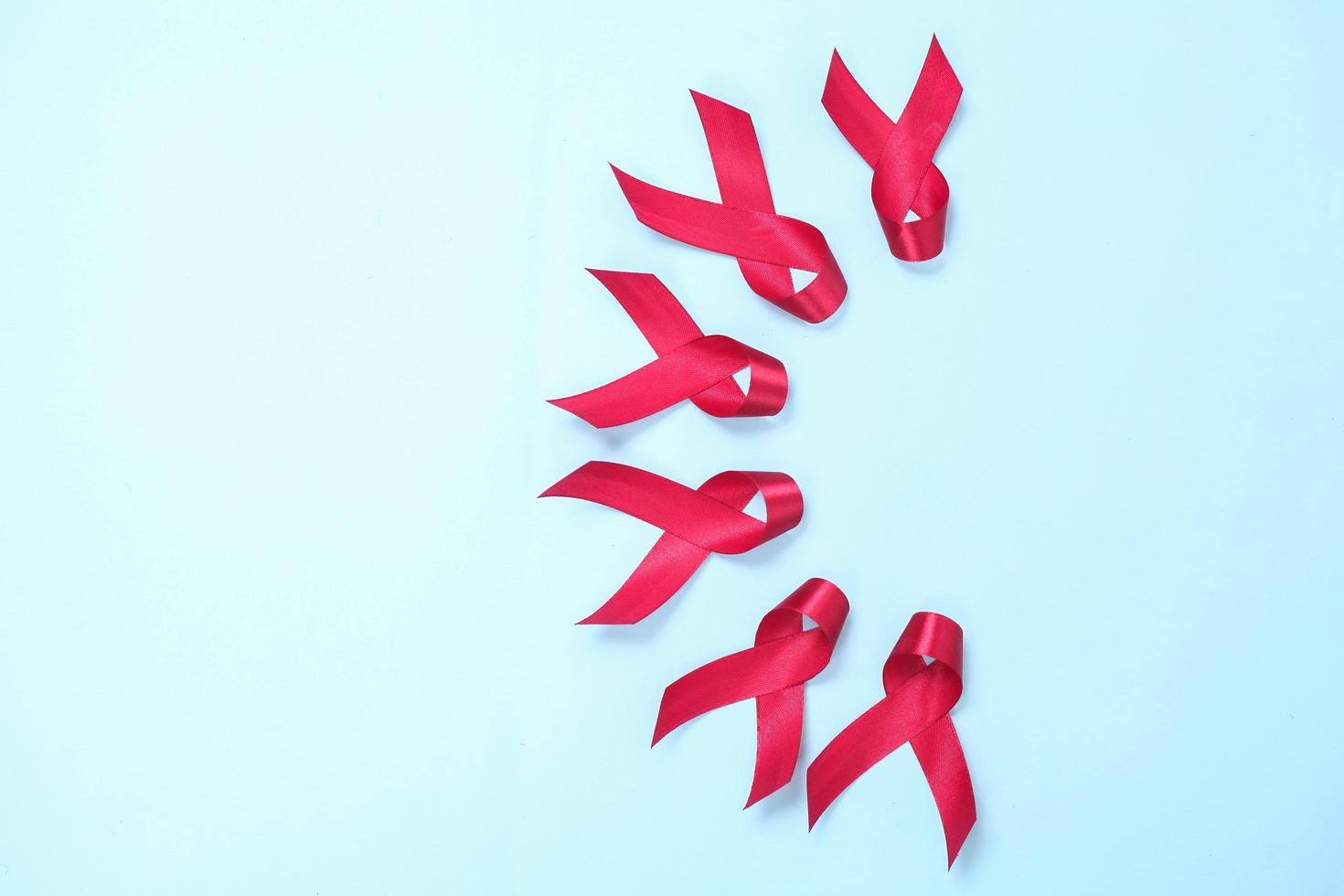 red ribbon composed of symbols of AIDS against HIV virus isolated on blue background photo