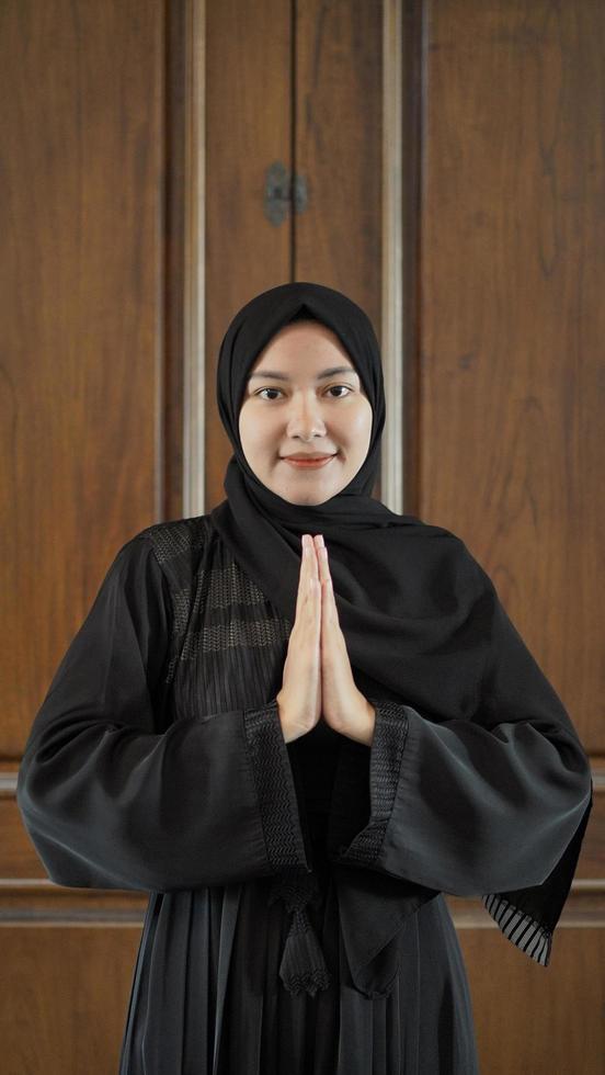 woman in black Muslim dress gesturing sorry in mosque photo