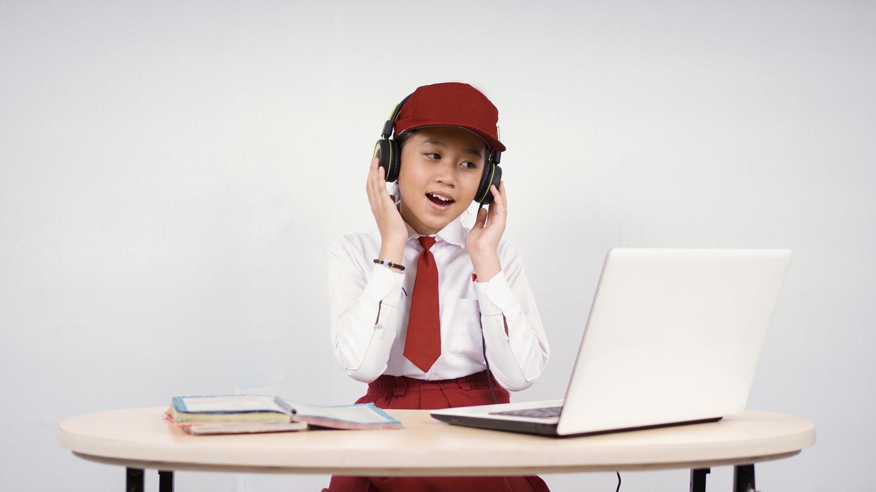 Beautiful elementary school girl listening while studying isolated on white background photo