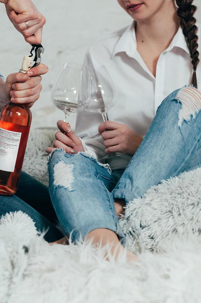 pareja joven en jeans abre una botella de vino rosado foto