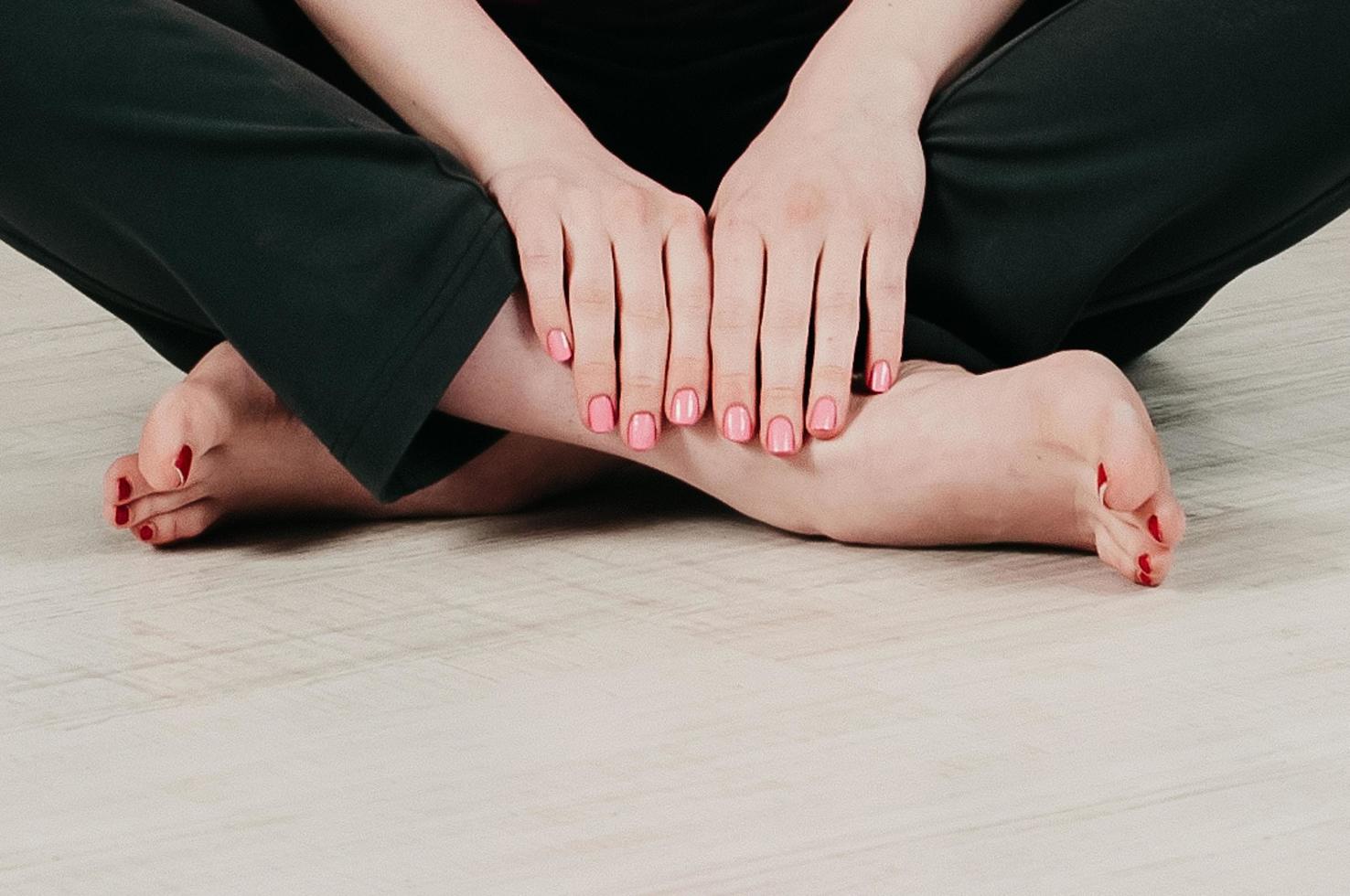 vista de cerca de una chica con las piernas cruzadas en el suelo, manicura rosa foto