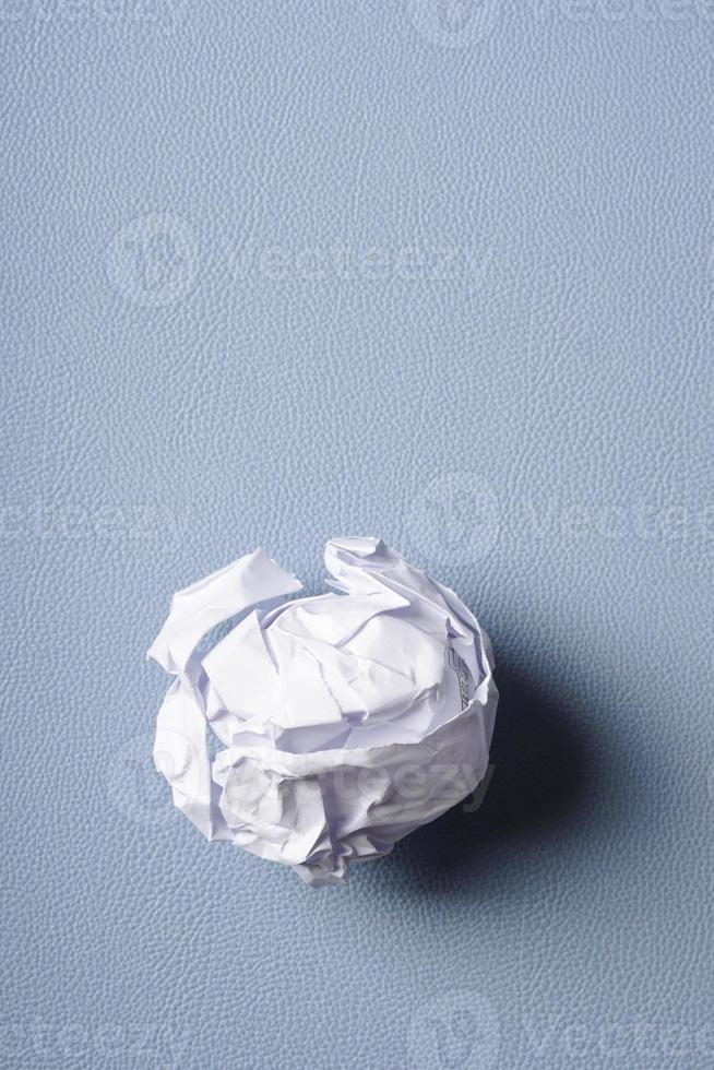 crumpled-up ball of paper on blue background photo