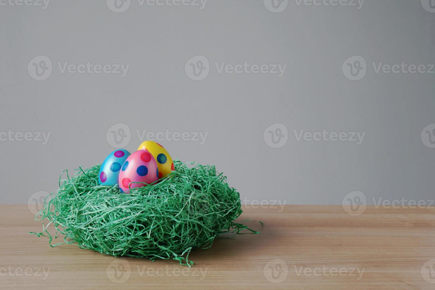 easter eggs in an artificial grass nest on table photo