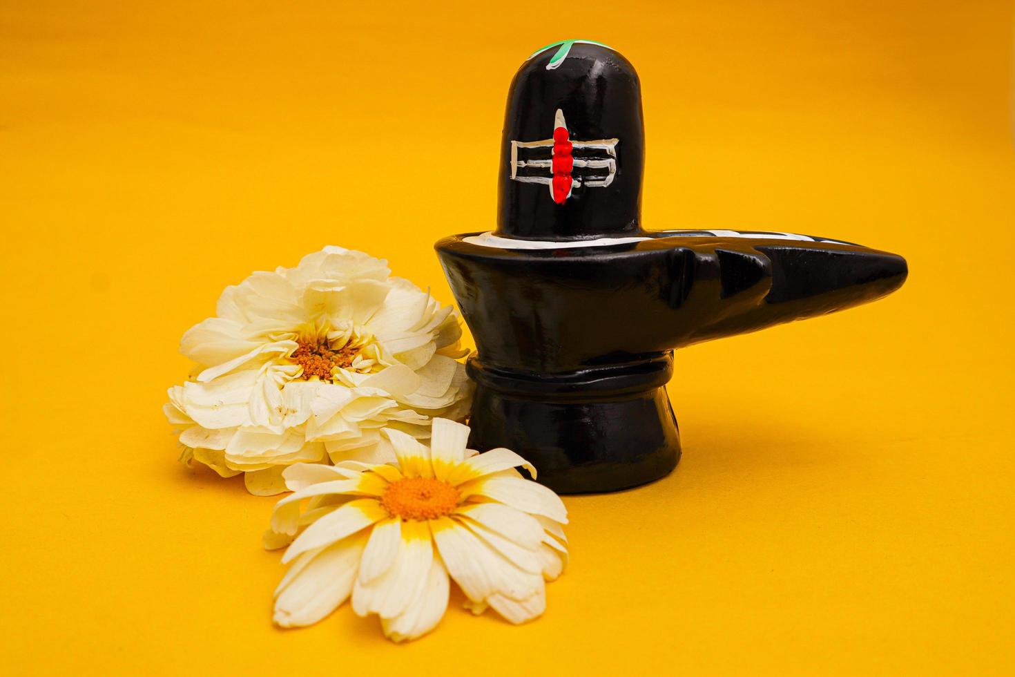 Shiva Linga decorated with flowers on yellow background. photo