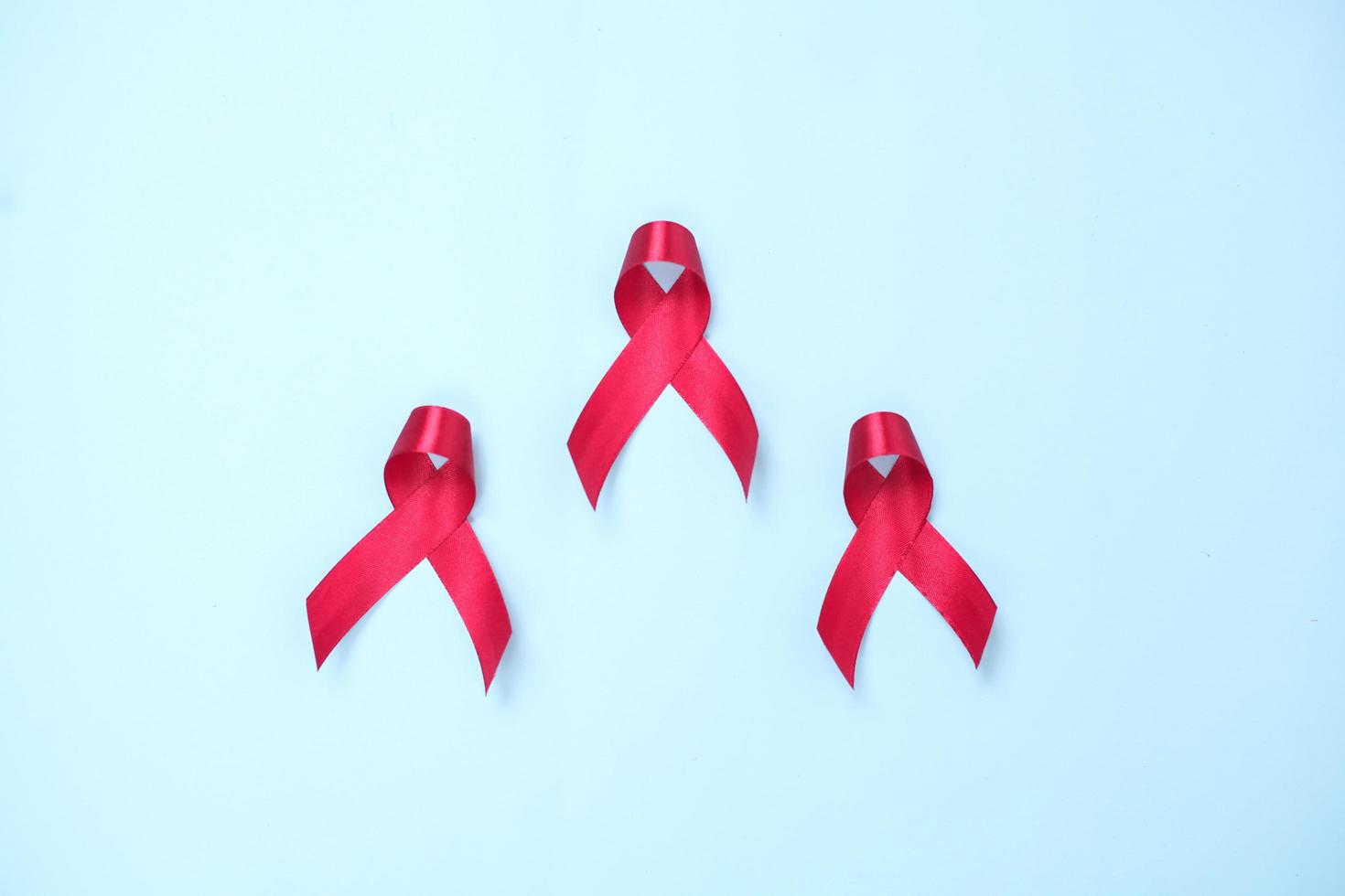 red ribbon composed of symbols of AIDS against HIV virus isolated on blue background photo