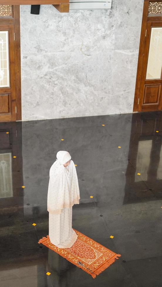 Asian Muslim woman praying alone without imam in mosque photo