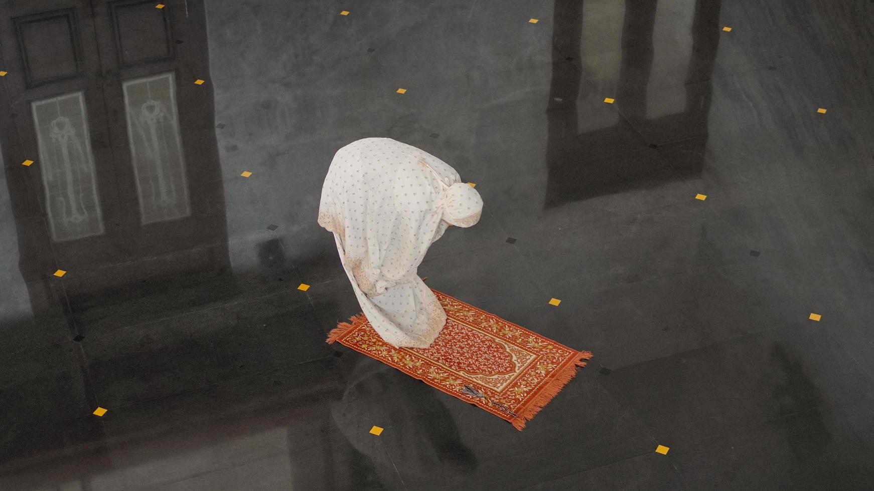 Asian Muslim woman praying alone without imam in mosque photo