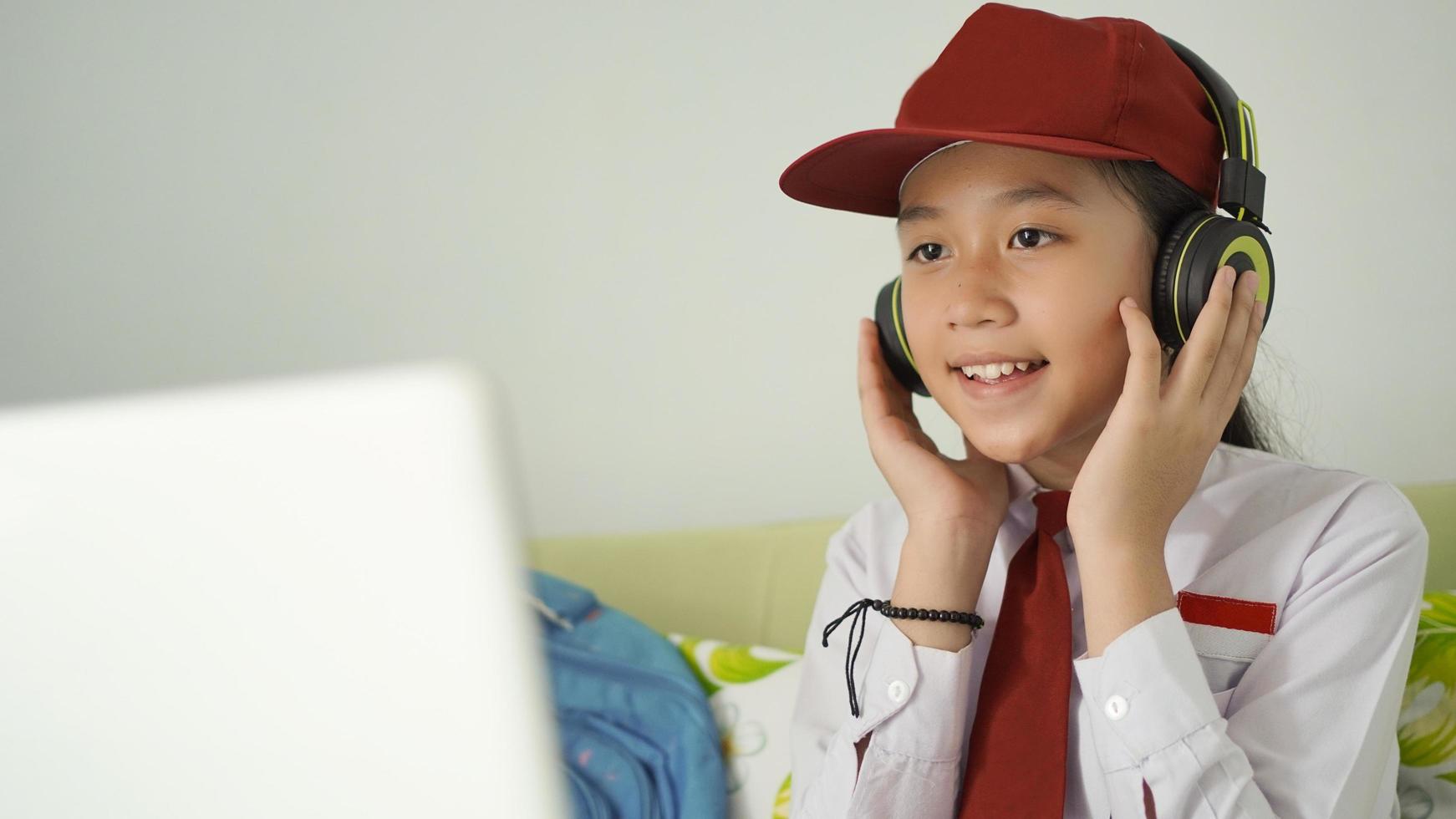 asian elementary school girl studying online listening carefully at home photo