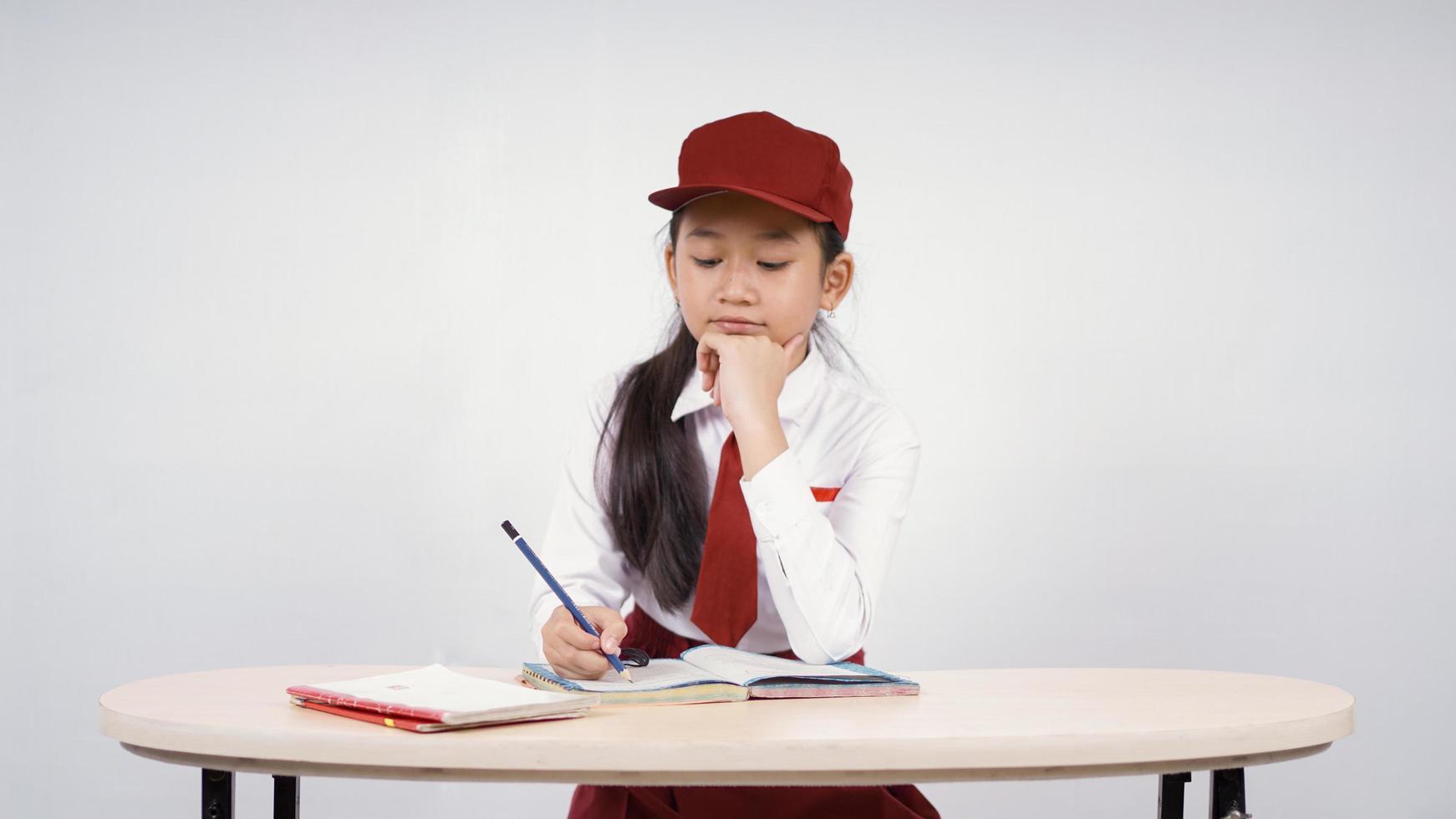 Elementary school asian girl writing enjoying isolated on white background photo