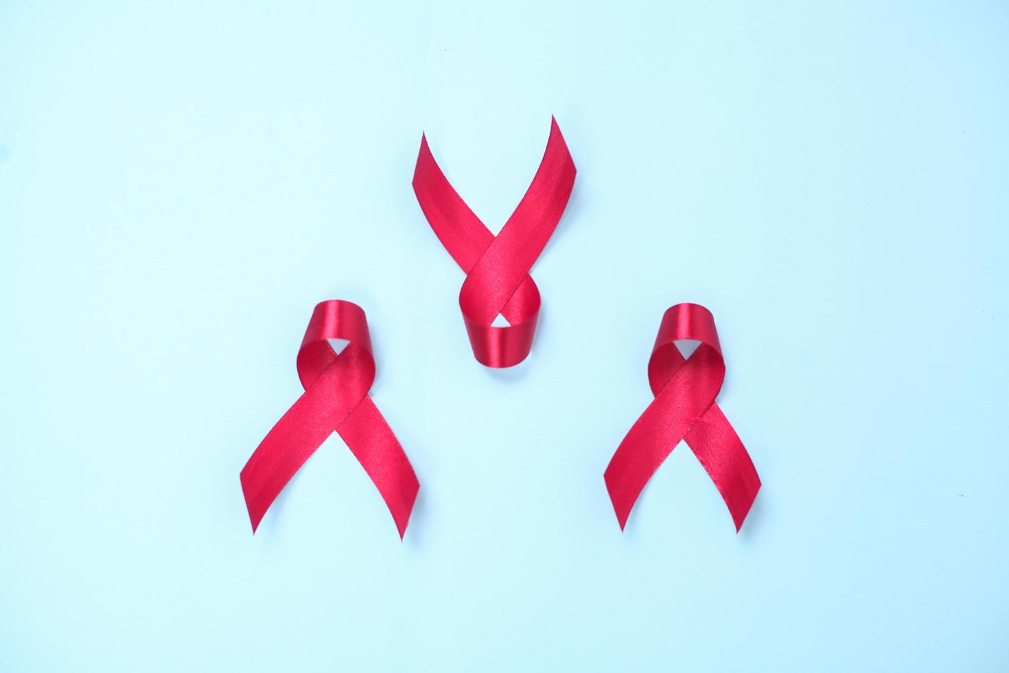 red ribbon composed of symbols of AIDS against HIV virus isolated on blue background photo