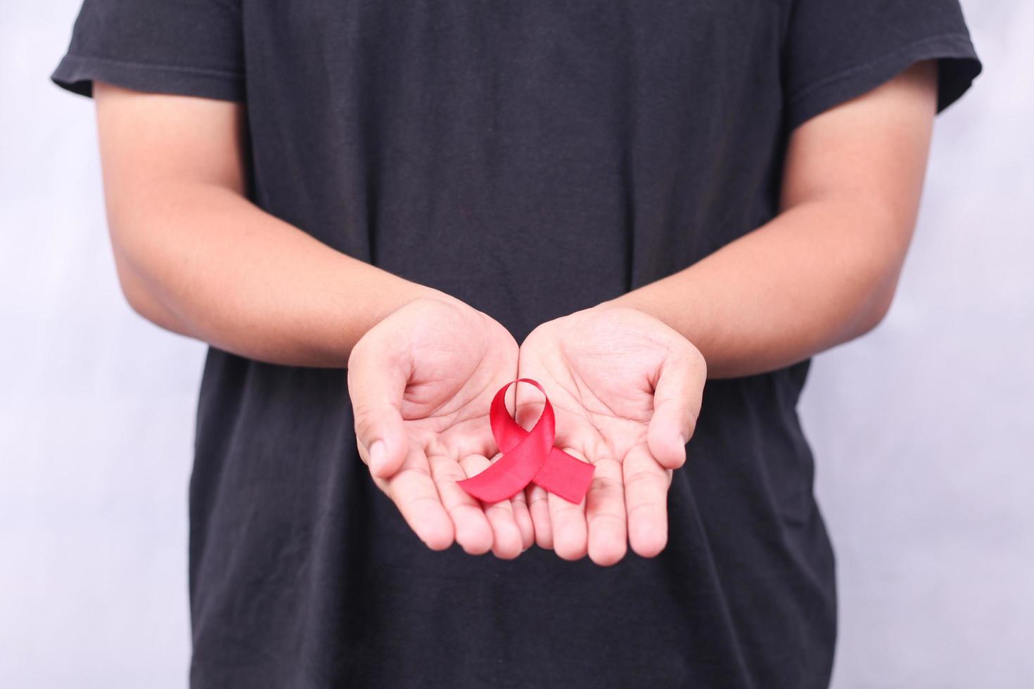 Símbolo de sida con cinta roja en la mano aislado sobre fondo blanco. foto