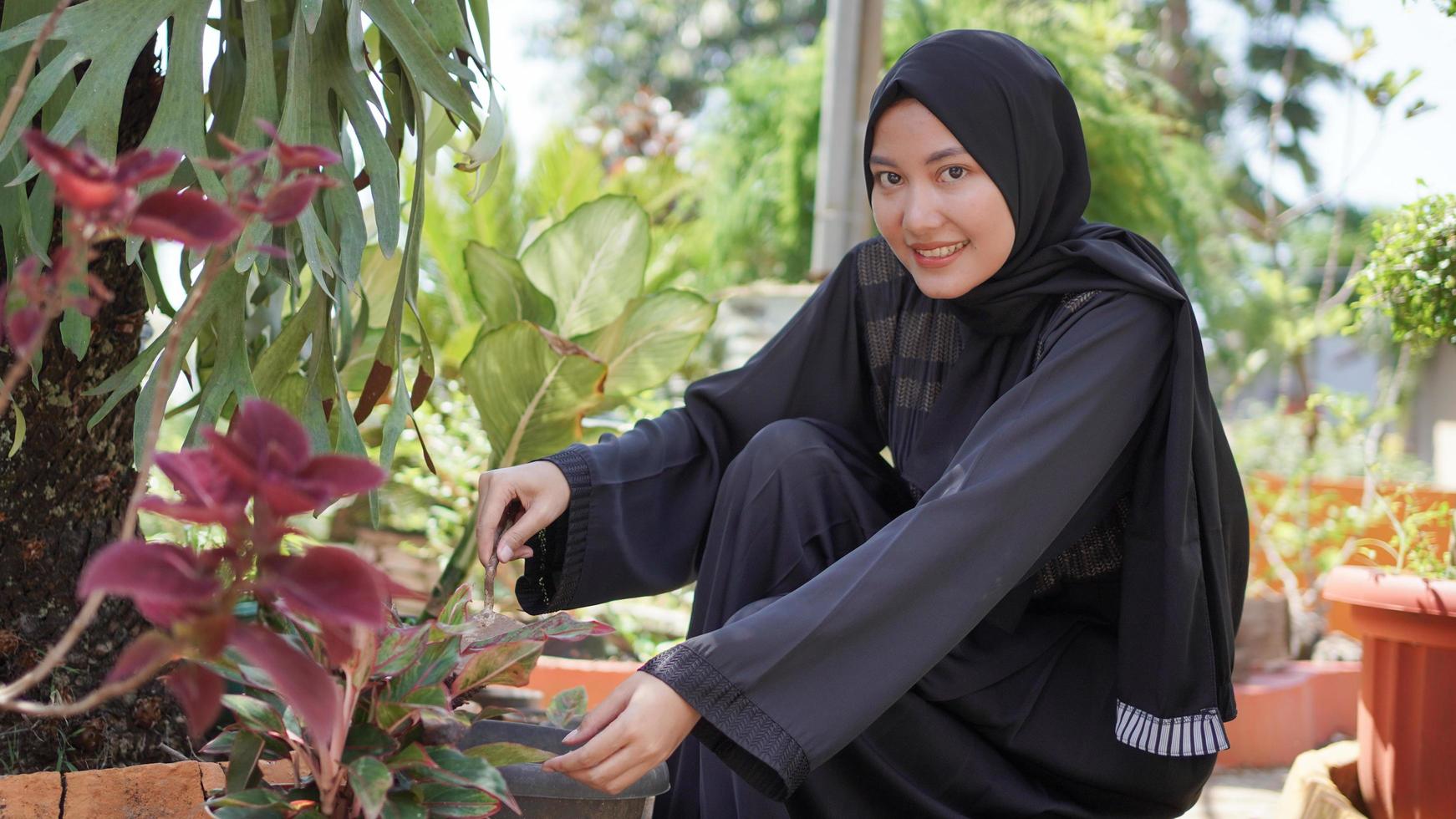 the beauty in hijab who likes to plant flowers in the garden photo