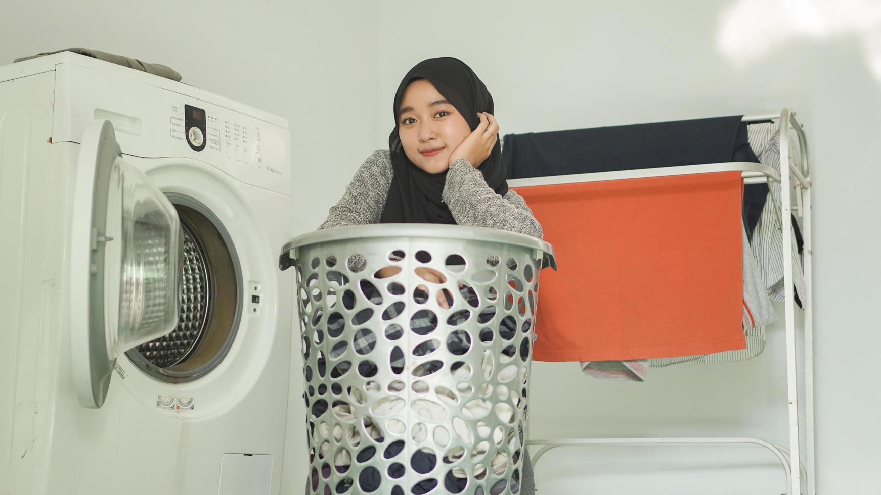 bella mujer asiática con hiyab que lavará su ropa sucia en casa foto