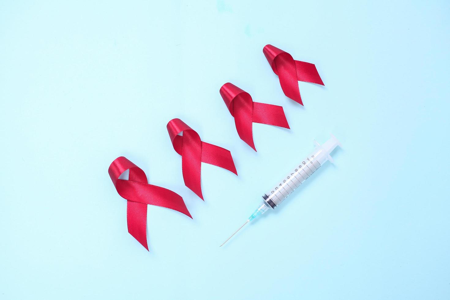 red ribbon composed of symbols of AIDS against HIV virus isolated on blue background photo