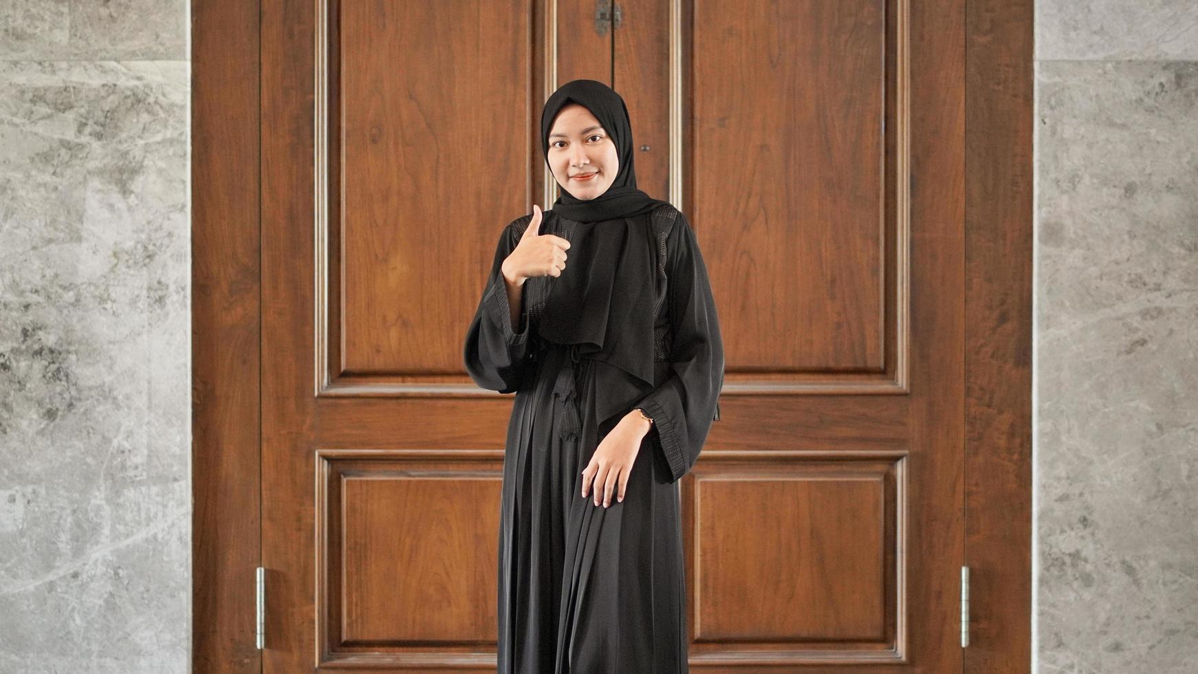 woman in black muslim dress gesturing ok at the door photo