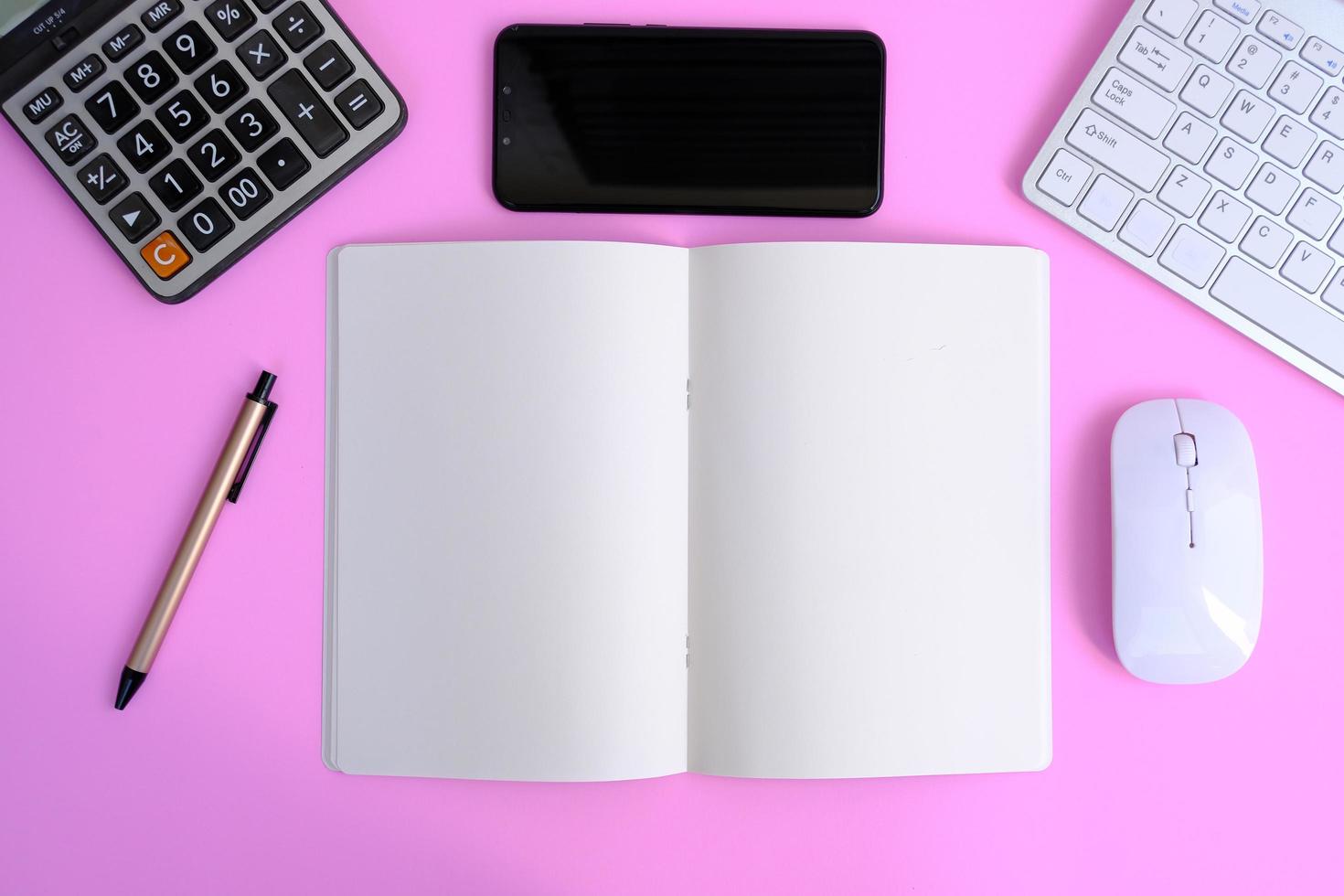 un cuaderno en blanco con bolígrafo se coloca en una mesa de oficina con herramientas informáticas y una variedad de materiales. antecedentes financieros y bancarios, endecha plana, vista superior foto