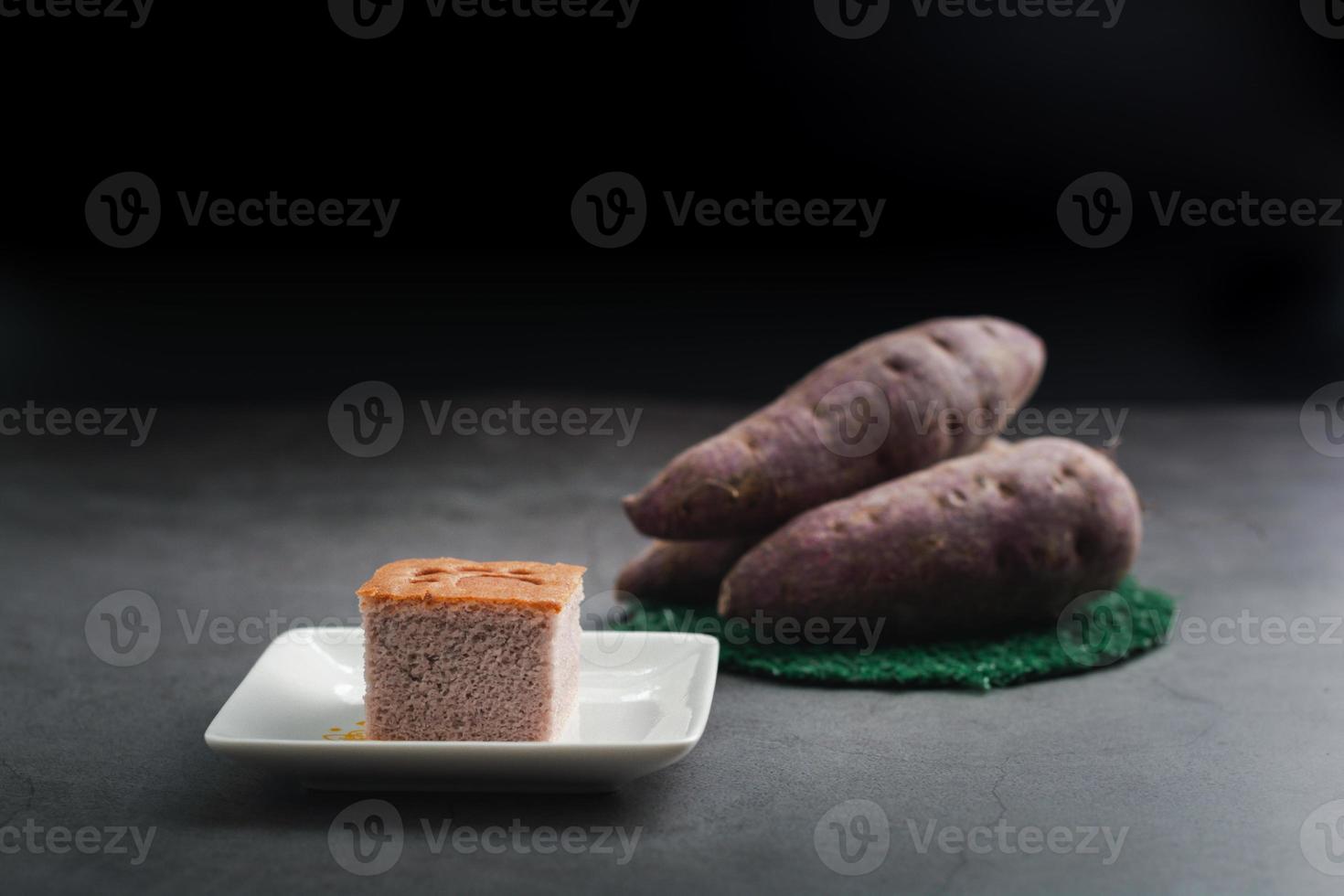 A square-cut of sweet potato cake on a white plate in the kitchen. Bakery and beverage concept. photo