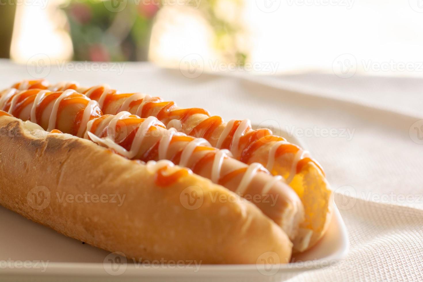 hot dog con pan y ketchup, mayonesa en plato blanco. sándwich de salchicha para el almuerzo. concepto de comida rápida. foto