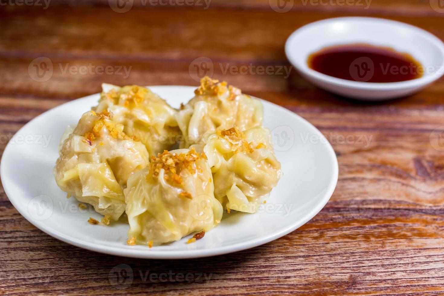 Chinese Steamed Dumpling, Shumai on white dish served with soy sauce on wooden table. Delicious Dimsum pork. photo