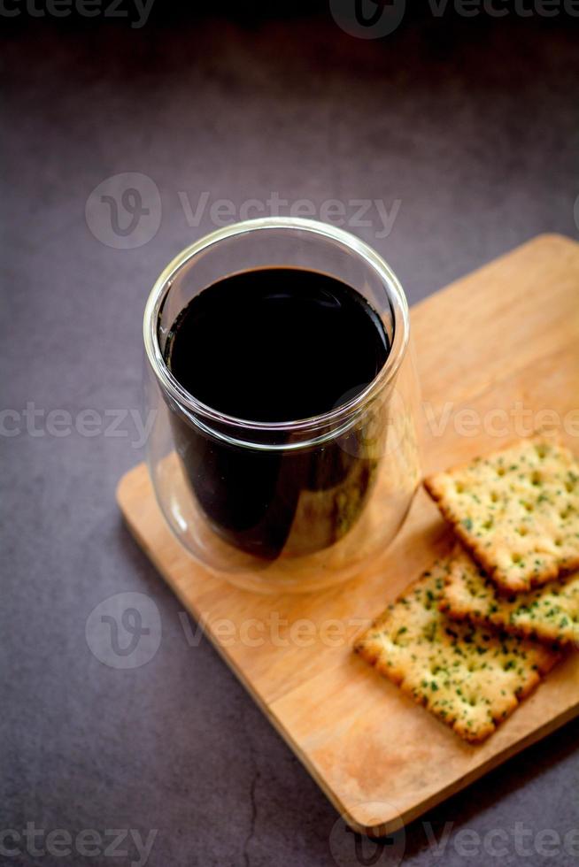 Espresso or black coffee served with cracker on wooden table and dark background. Energy drink in the morning concept. photo