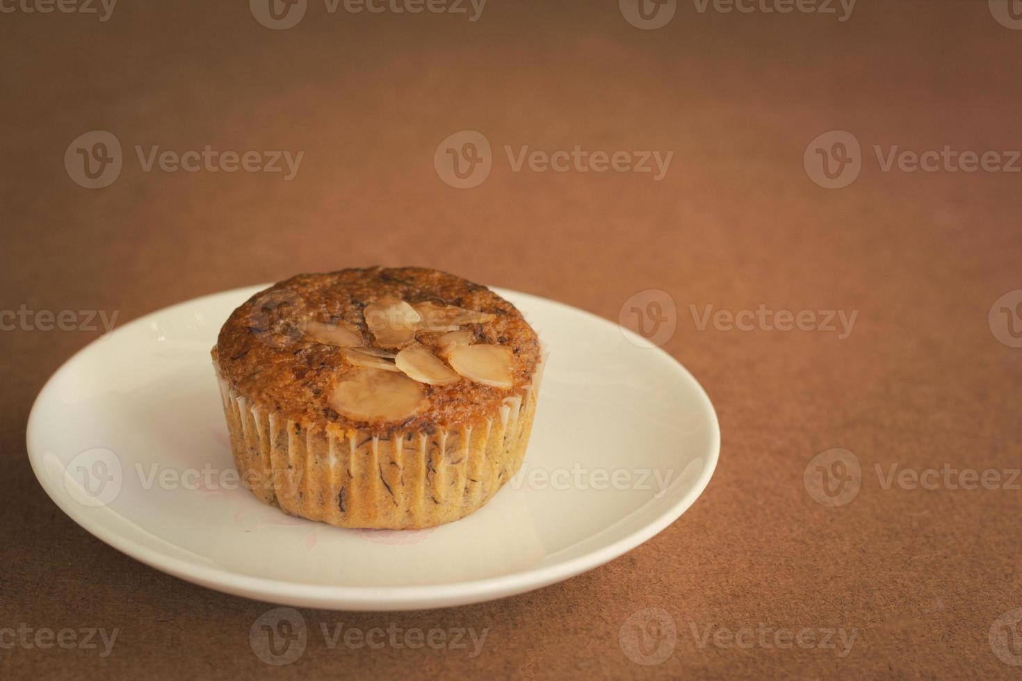 Delicious banana cup cake on white dish and wooden table with copy space. Homemade bakery. photo
