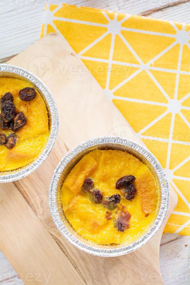 Bread pudding with black rasins in round foil cup on wooden tray. Delicious custard for coffee times. photo