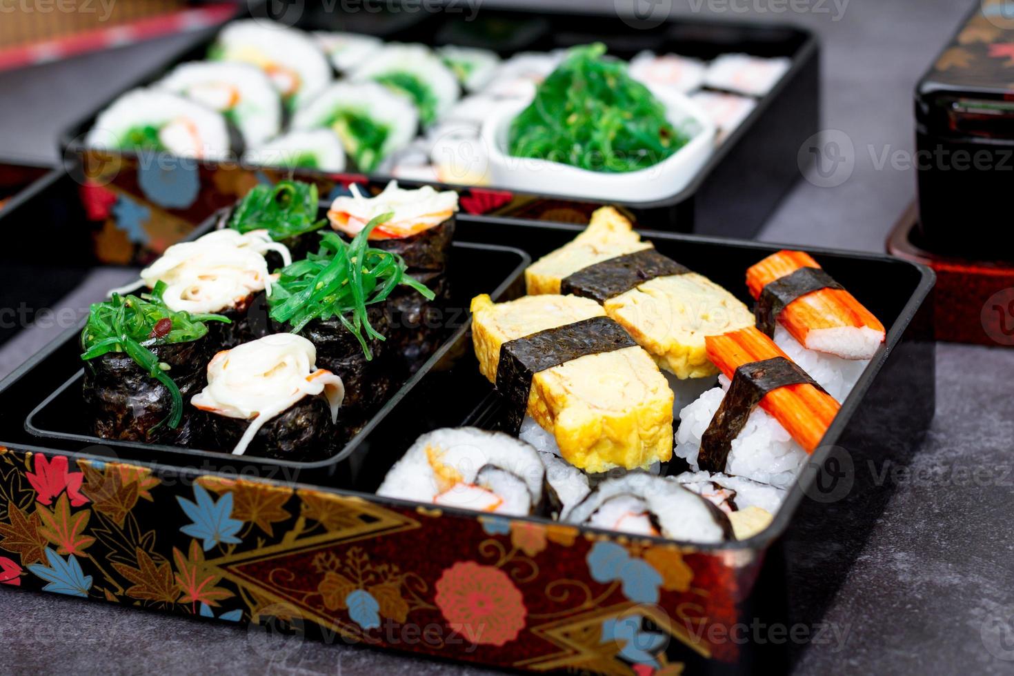 Set of variety sushi, Tamagoyaki, crabsticks sushi and maki in bento box served with soy sauce and wasabi. Delicious japanese food. photo