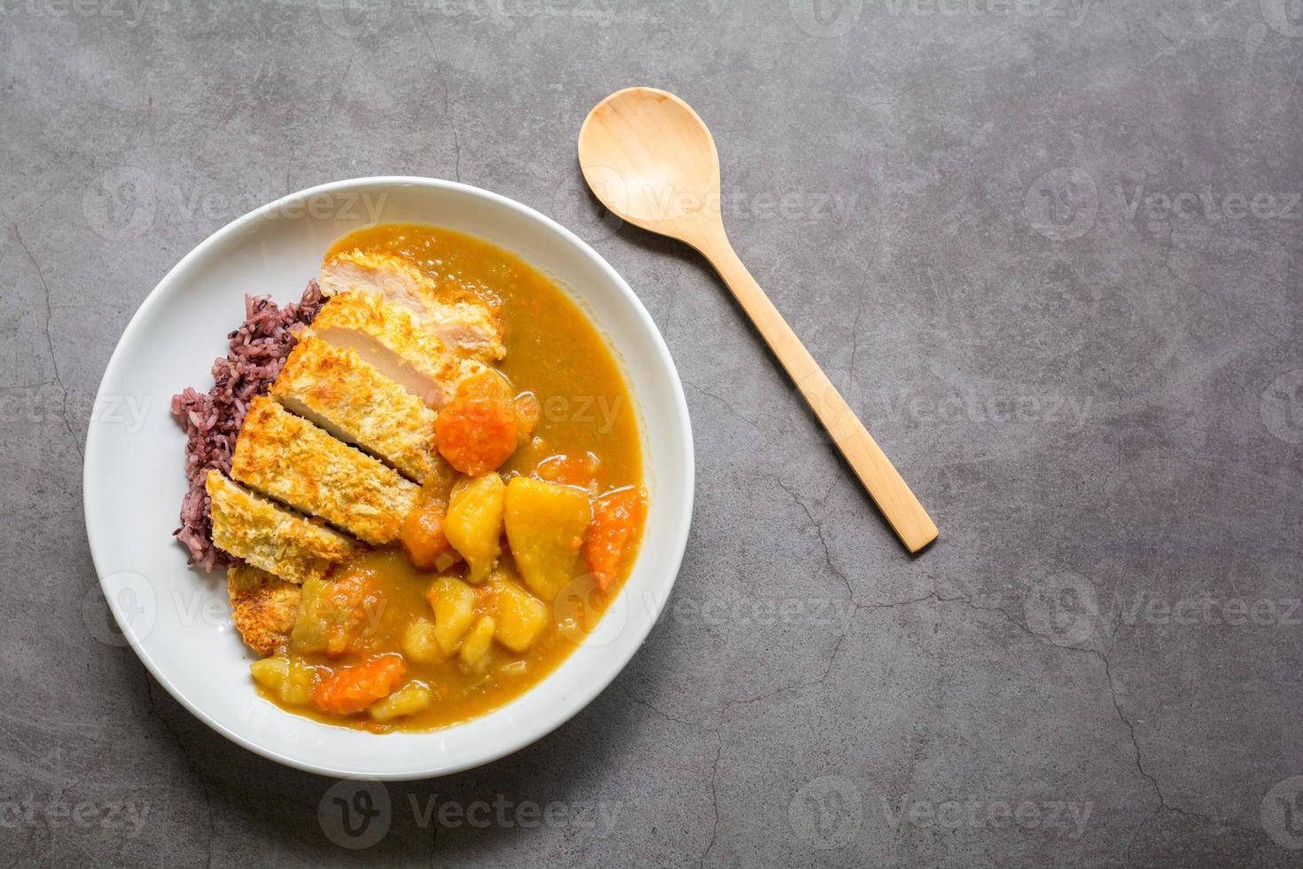 Japanese curry with rice, carrot, potato and deep fries chicken in white dish on table. photo