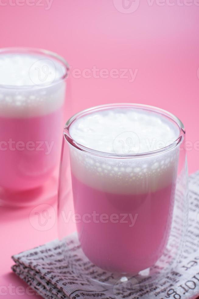 Summer drink concept. Strawberry pink milk with froth milk in clear glass on pink background. photo