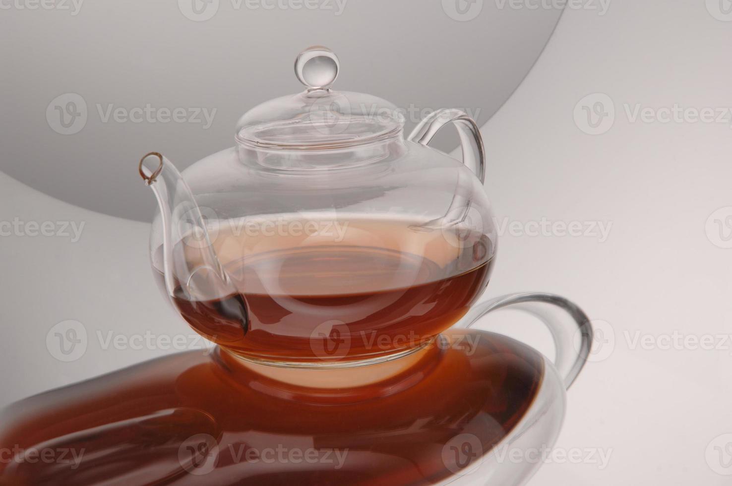 Transparent glass teapot and cup with tea photo