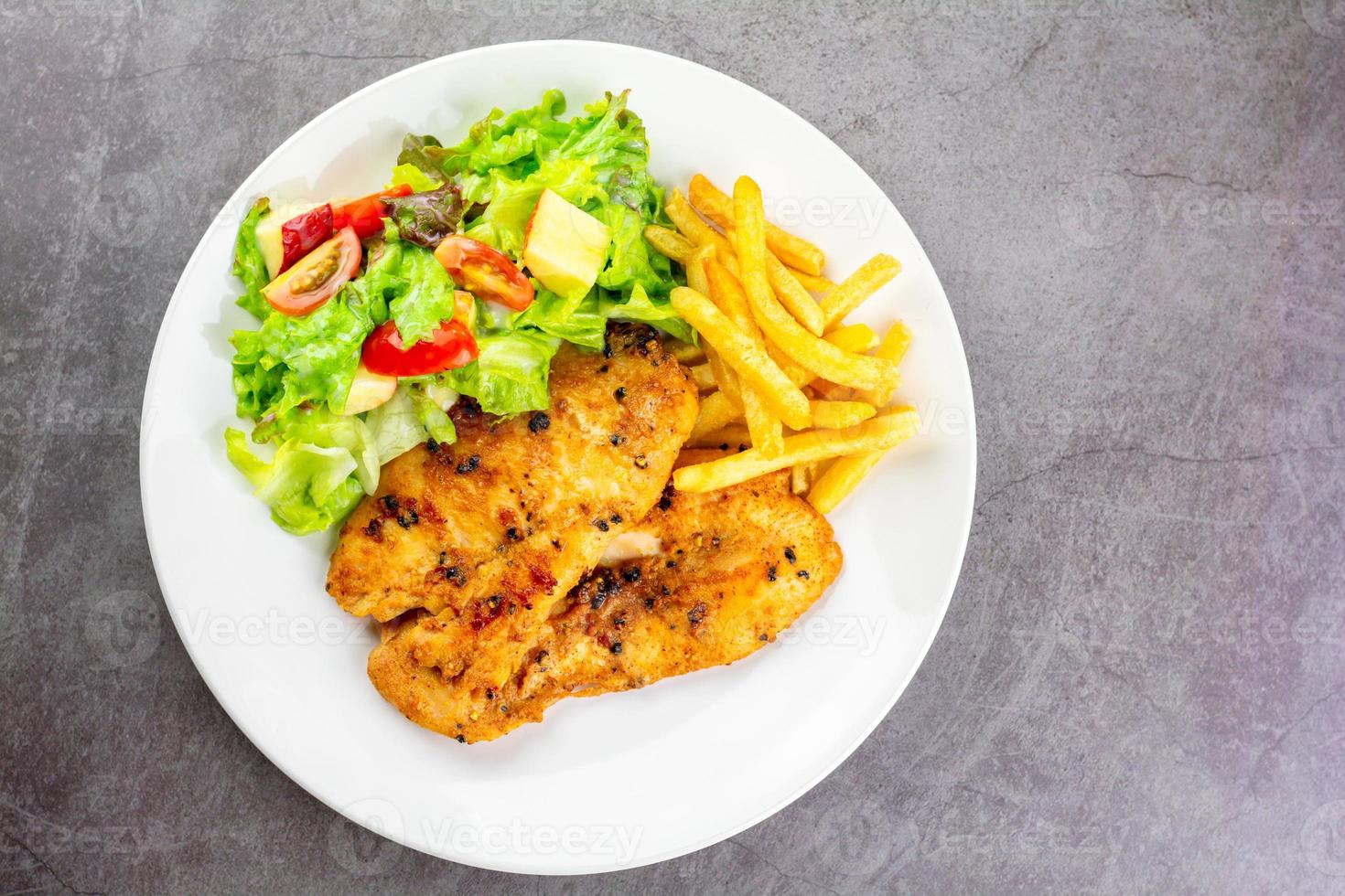 concepto de comida casera. filete de pechuga de pollo con pimienta negra servido con ensalada y papas fritas en un plato blanco. alimentos ricos en proteínas. vista superior. foto