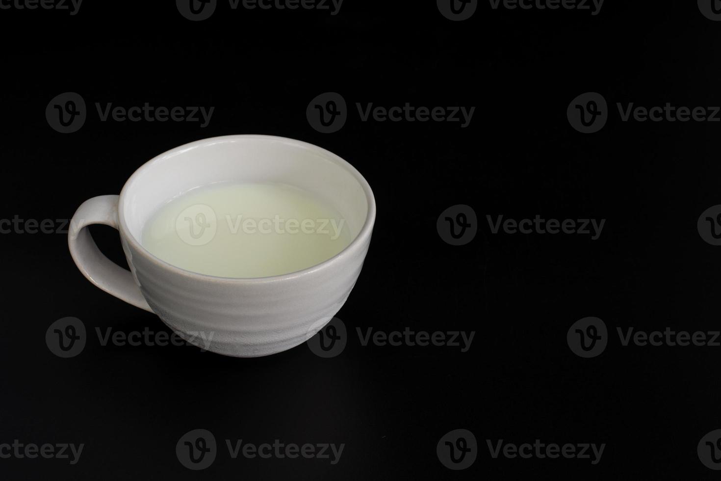 Side view of white cup of milk on black background with copy space. High protein and calcium. Healty beverage. photo