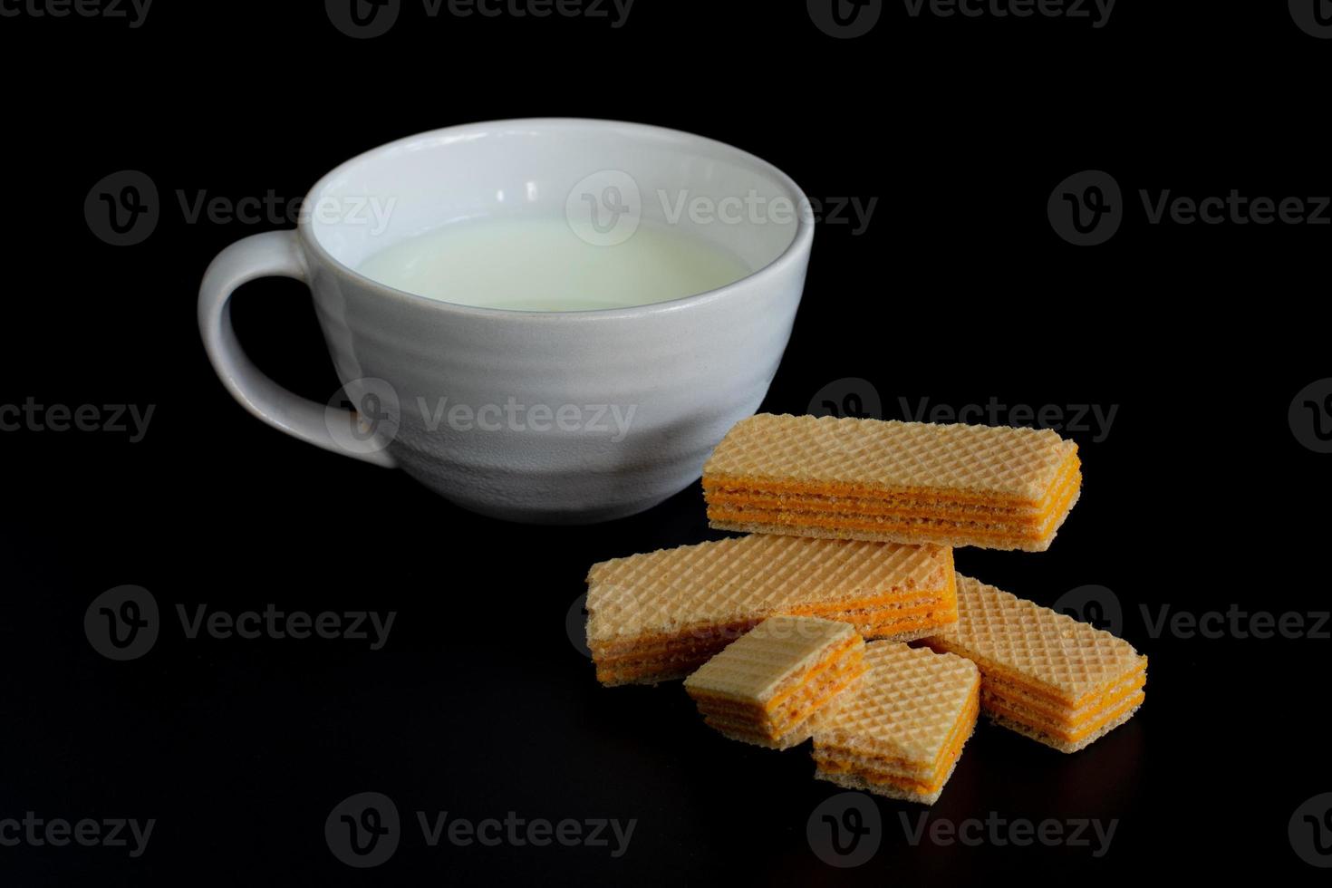 Side view four wafer and cup of milk on black background with copy space. photo