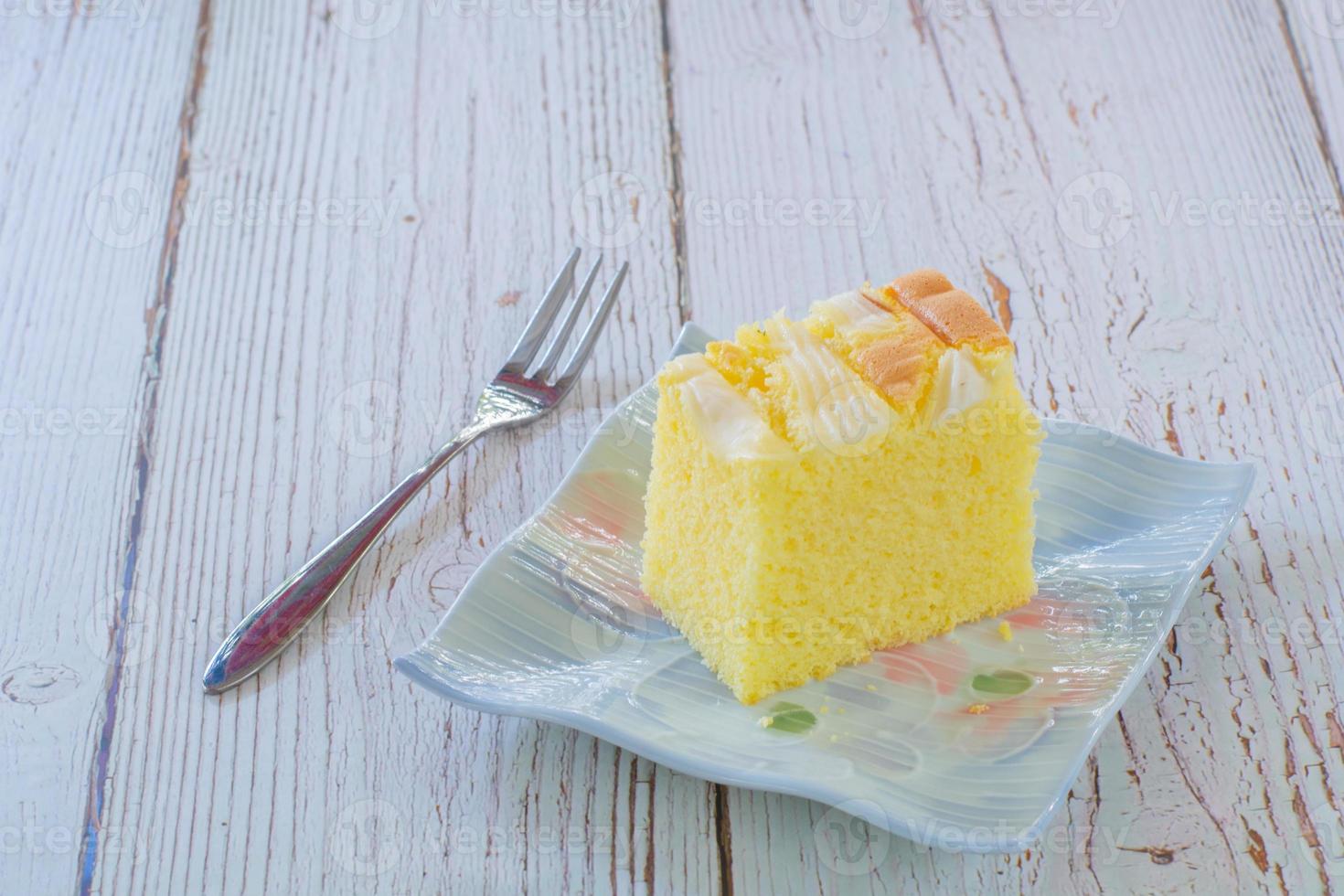 Piece of vanilla chiffon coconut cake on square plate on wooden table. Delicious small bakery for coffee and tea times. Copyspace for your text. photo
