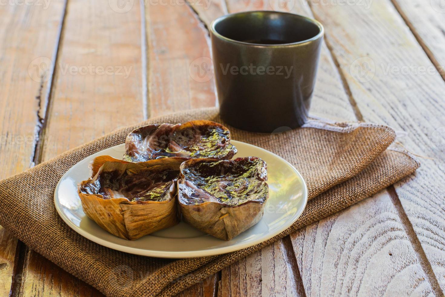 pastel de arroz pegajoso negro nian gao en una taza de plátano seco sobre un plato blanco y una mesa de madera. merienda tradicional en año nuevo chino. foto